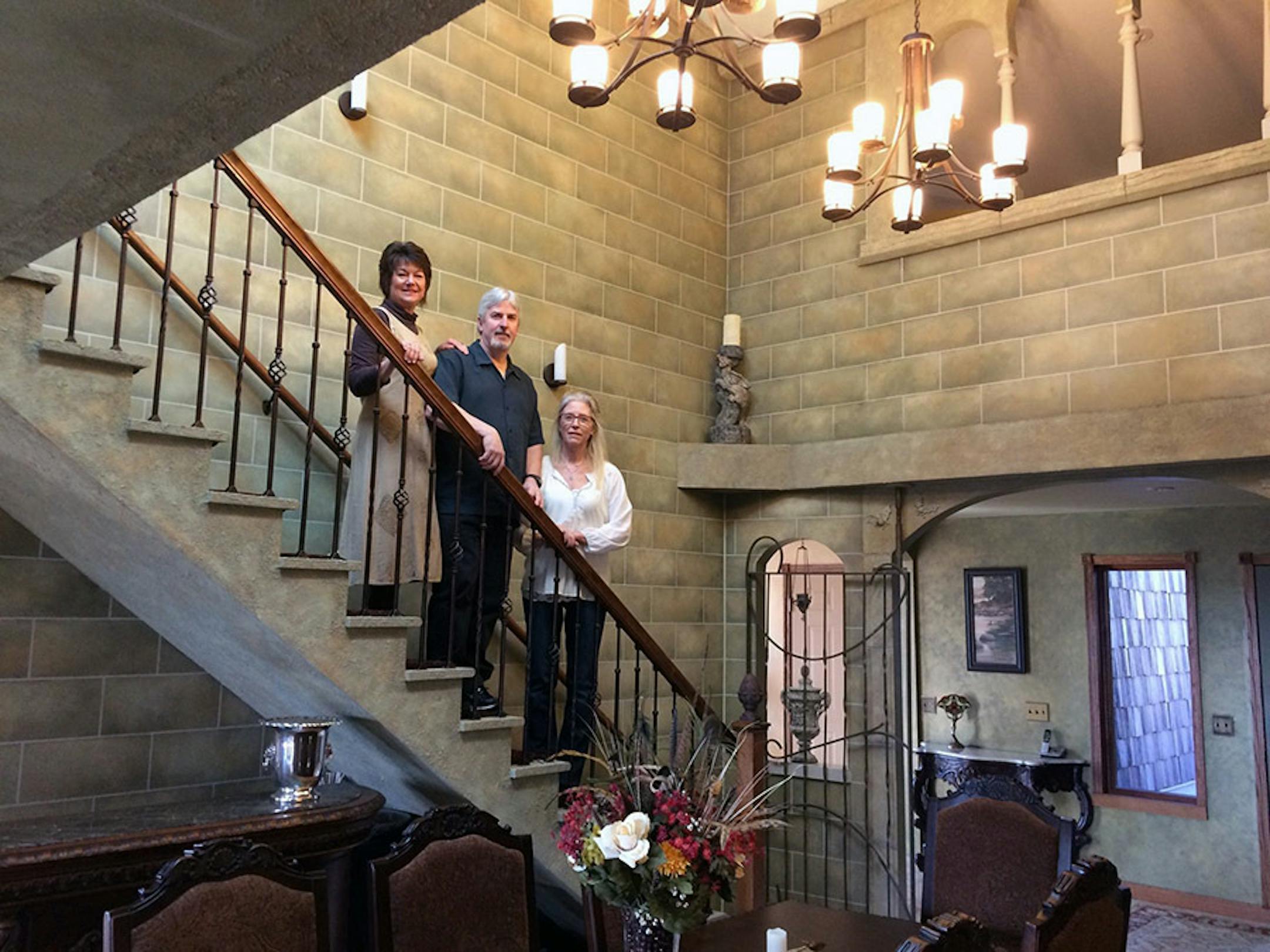 Homeowners Mecca and Dave Page, left to right, with artist Jennifer Kranz, in the castle-inspired courtyard that they created inside the Pages' Hastings dining room.