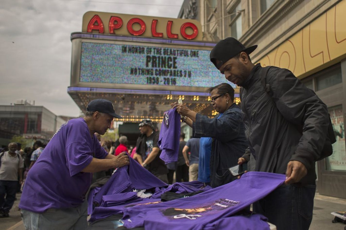 Fans buy t-shirts of Prince at a memorial site created outside the Apollo Theater in New York , Friday, April 22, 2016. The pop super star died Thursday at the age of 57.