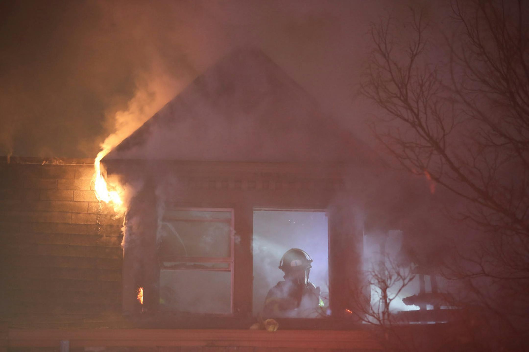 A firefighter works to extinguish a fire Monday night on the third floor of a building on Aldrich Avenue South in Minneapolis, Minn. while flames still flickered just outside. There were no injuries.