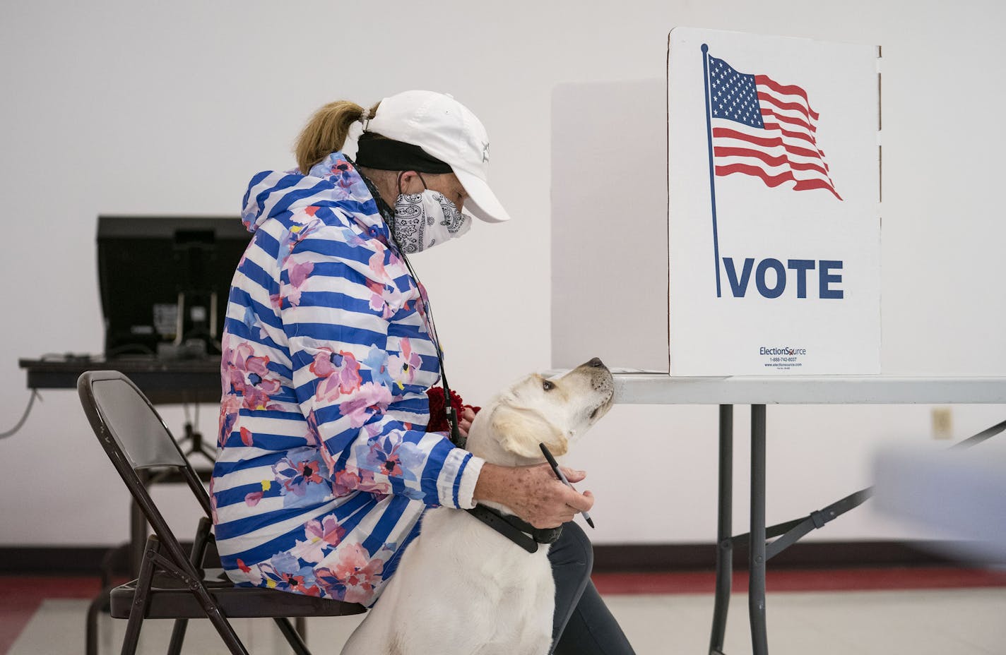 Catherine Anderson sits with her dog, Ivy, as she votes in the Wisconsin Primary at the Billings Park Civic Center in Superior, Minn., Tuesday, April 7, 2020. (Alex Kormann/Star Tribune via AP)