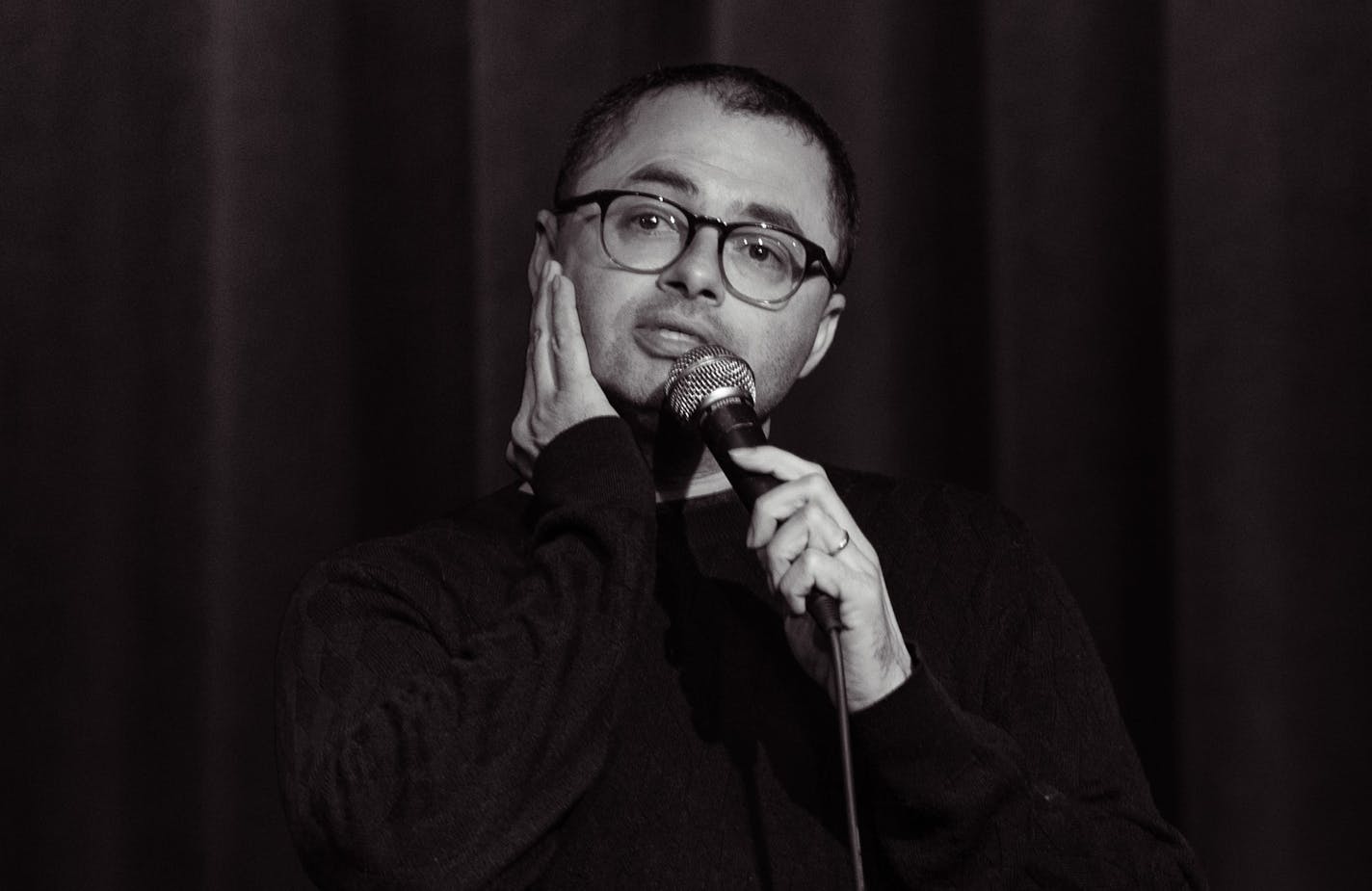 Comic Joe Mande on stage, black and white photo.