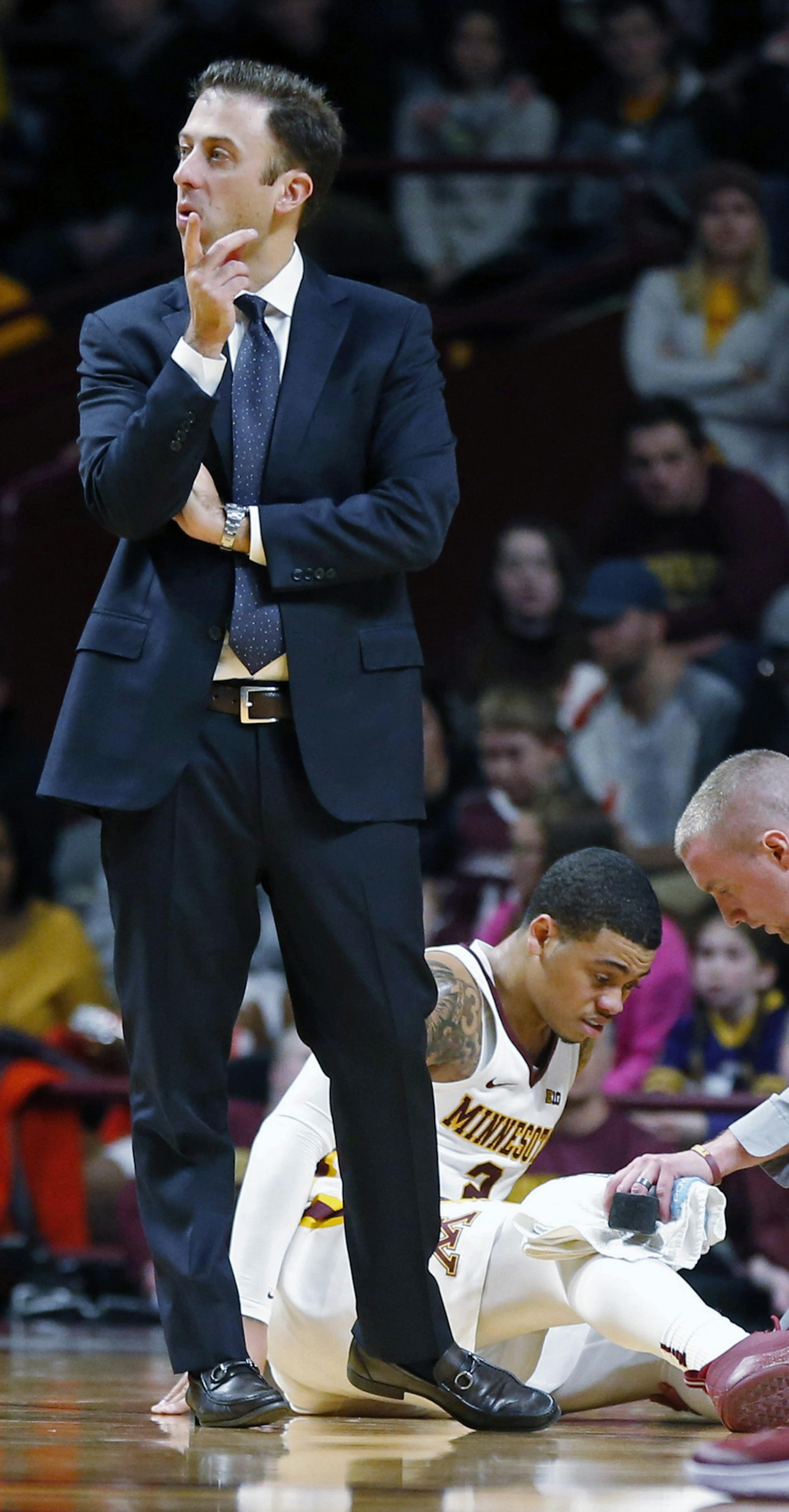 Minnesota head coach Richard Pitino, left, stands by as Nate Mason is attended to after being injured in the second half of an NCAA college basketball game against Florida Atlantic, Saturday, Dec. 23, 2017, in Minneapolis. (AP Photo/Jim Mone)