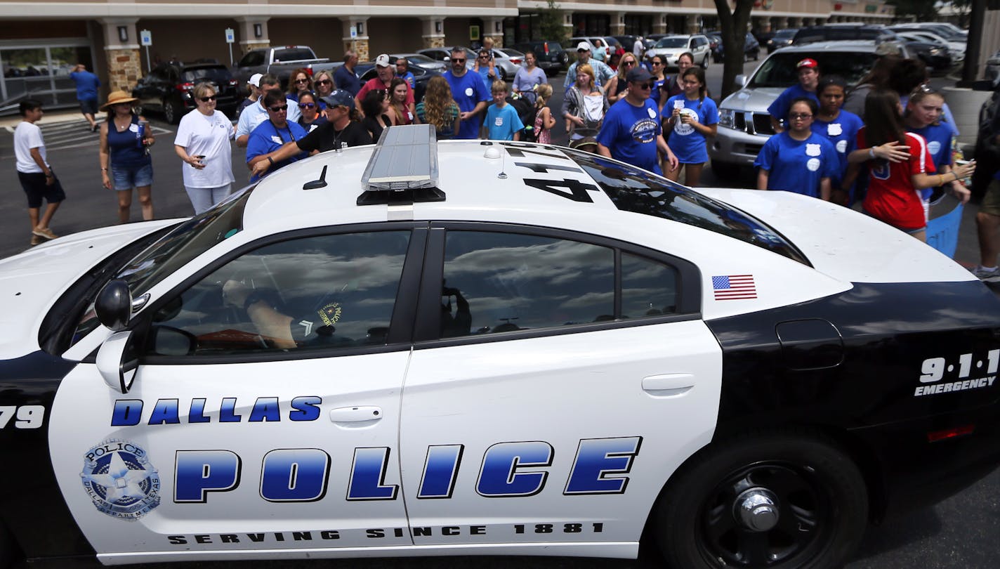 A Dallas police car drives by a fundraising event for officer Michael Smith, Sunday, July 10, 2016, in Farmers Branch, Texas. Smith was one of five officers killed Thursday by Micah Johnson during a protest in Dallas. (AP Photo/Tony Gutierrez)