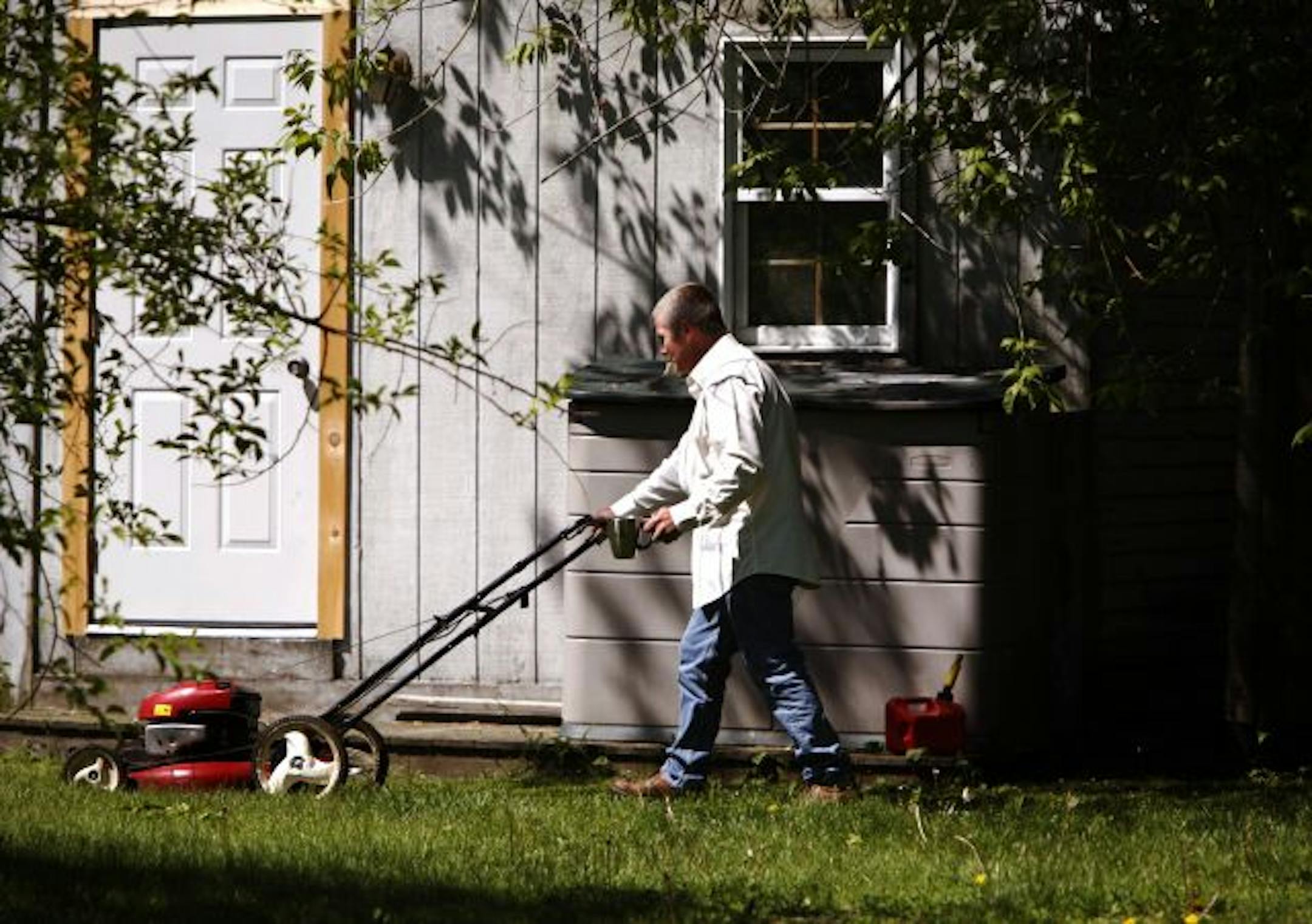 This June 1, 2009 photo shows Bobby Landry mowing the lawn near his apartment at the Tedford Housing family shelter in Brunswick, Maine.