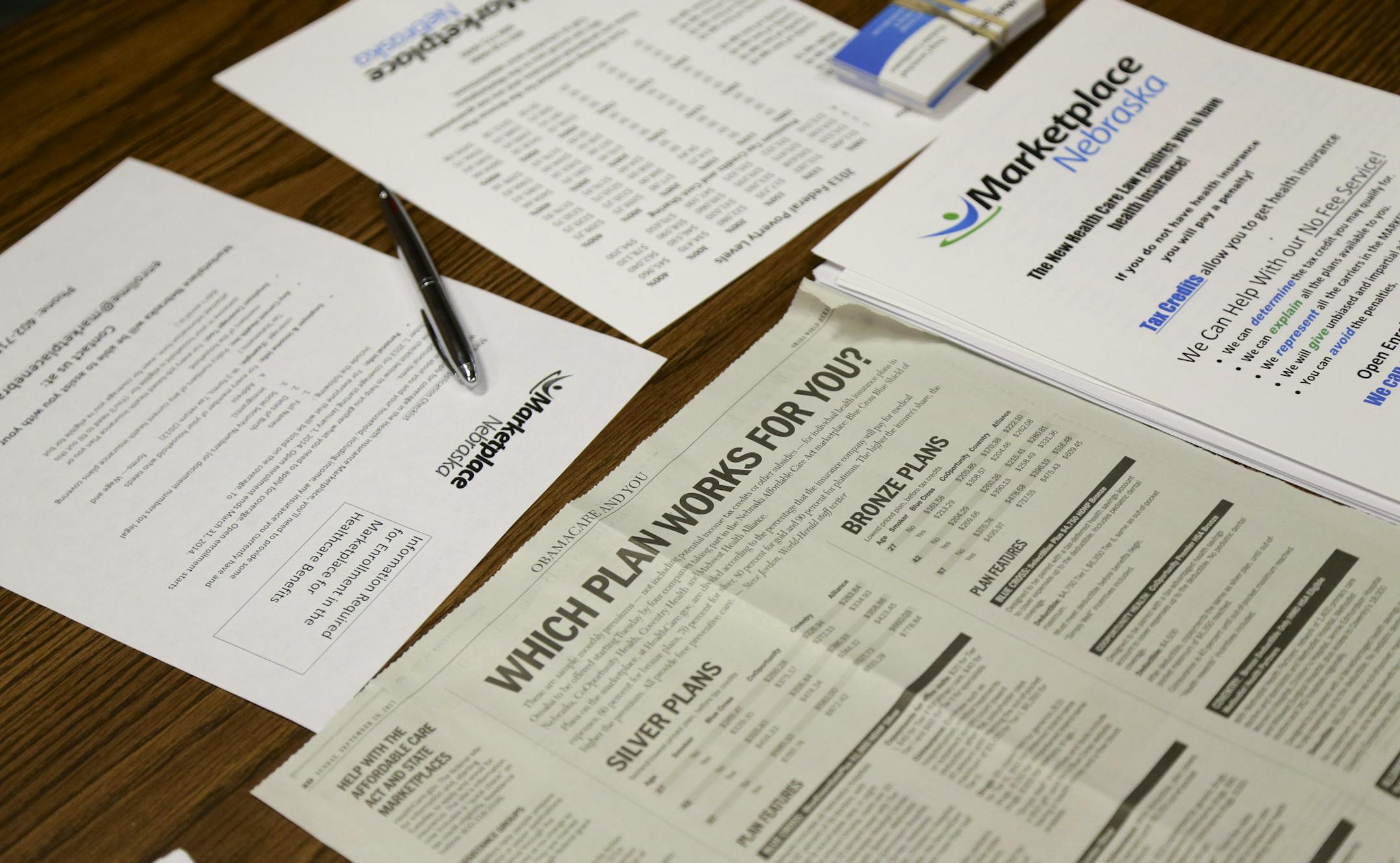 Forms and a newspaper article are spread on a table as a representative of Marketplace Nebraska, a health insurance broker under the new Affordable Care Act, explains the health insurance enrollment process and the options that are available at a seminar at the Willa Cather Omaha Public Library in Omaha, Neb., Tuesday, Oct. 1, 2013. The new health care marketplace got off to a bumpy start on Tuesday, with computer problems that prevented Nebraska residents from signing up for insurance right awa