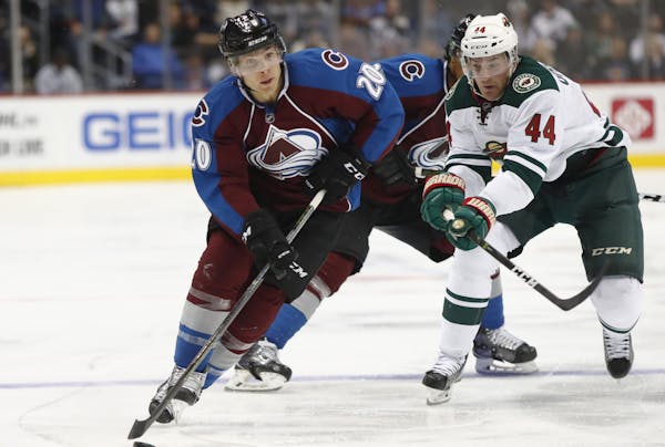 Colorado Avalanche right wing Ben Smith, front, looks to pass the puck as Minnesota Wild forward Tyler Graovac defends in the third period of an NHL p