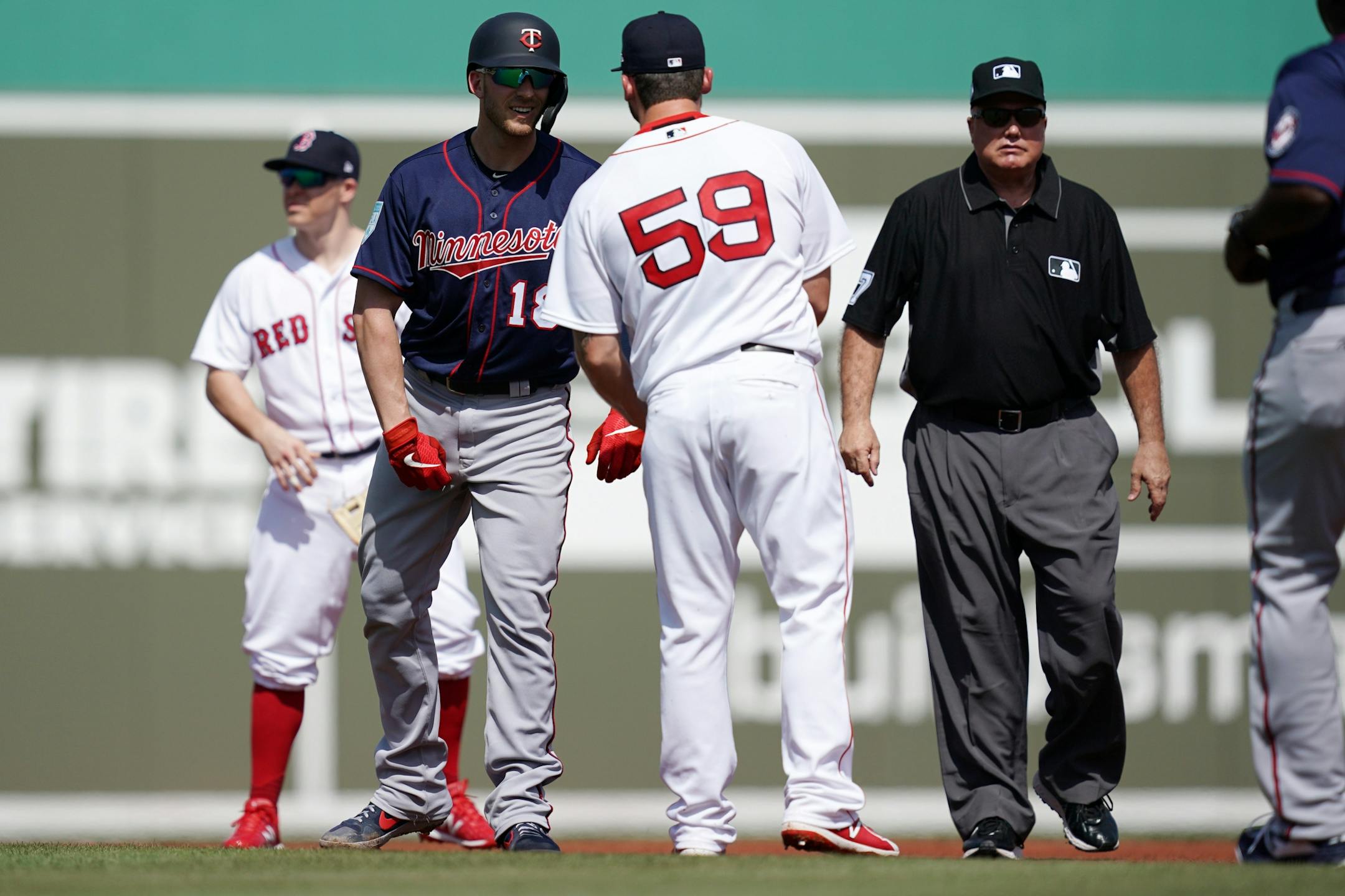Minnesota Twins catcher Mitch Garver (18) handed off his batting equipment to Boston Red Sox first baseman Sam Travis (59) after hitting a double during Sunday's game.
