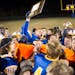 The Saint Michael-Albertville football team, including Josh Tracy, who holds the plaque, celebrate following a 38-12 win over Elk River at Saint Micha