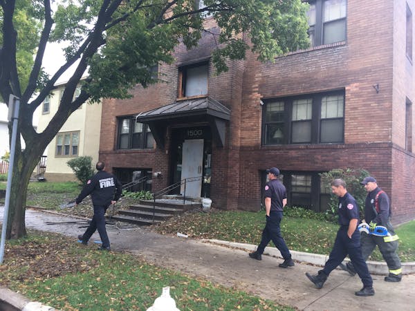 Officials from the Minneapolis Fire Department survey the damage Saturday morning after an apartment fire Friday night.