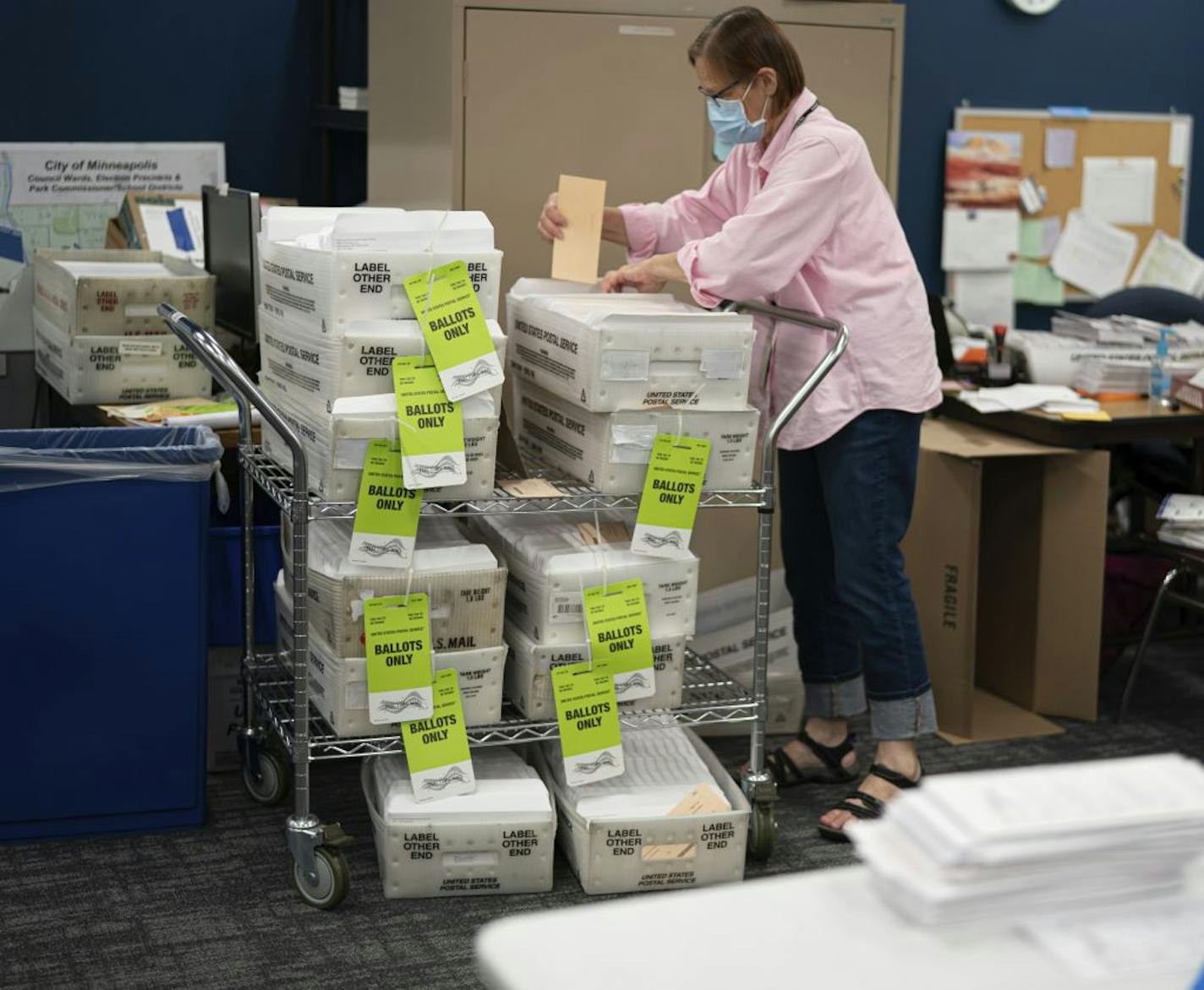 Laurie Mattila, adds a completed box of ballots to the stack of outgoing mail at Minneapolis Elections & Voter Services in Minneapolis.