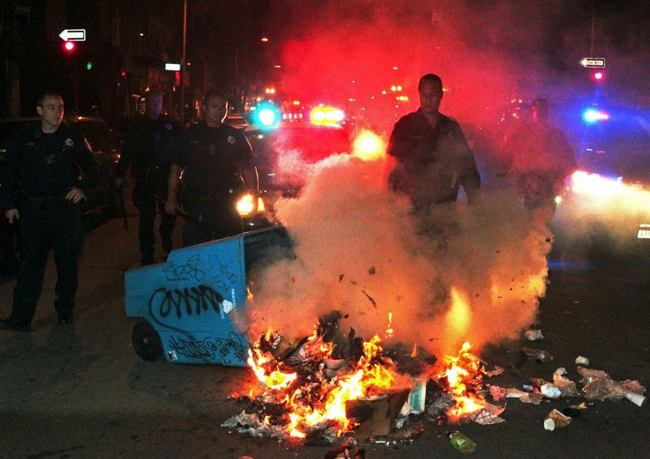 Oakland police officers work to extinguish a fire during a protest after George Zimmerman was found not guilty in the 2012 shooting death of teenager Trayvon Martin, early Sunday, July 14, 2013, in Oakland, Calif. Protesters angered by the acquittal Zimmerman held largely peaceful demonstrations in three California cities, but broke windows and started small street fires Oakland, police said.