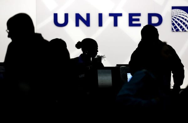 FILE - In this Saturday, Dec. 21, 2013, file photo, travelers check in at the United Airlines ticket counter at Terminal 1 in O'Hare International Air