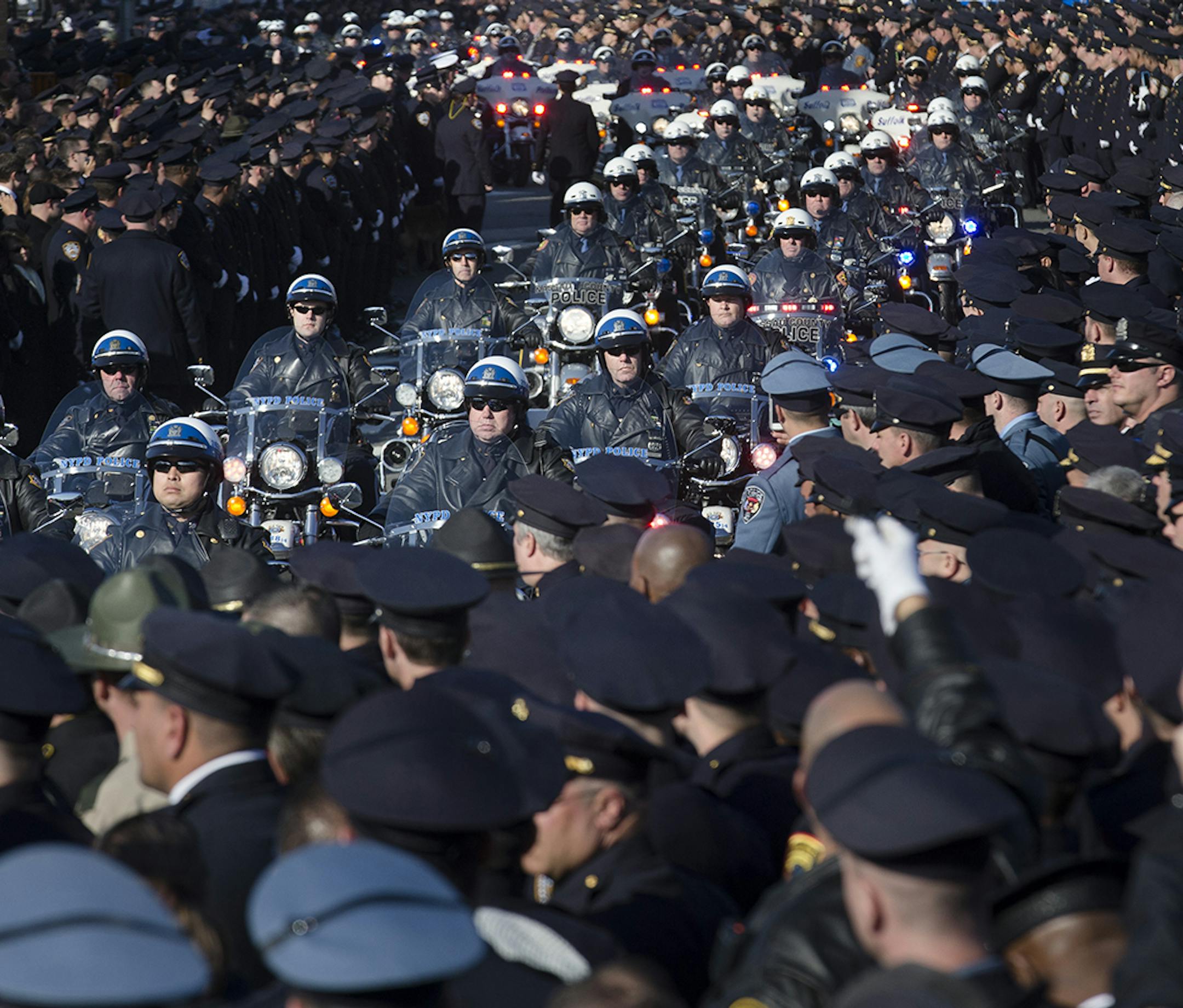 Motorcycle officers lead the funeral procession of New York city police officer Rafael Ramos in the Glendale section of Queens, Saturday, Dec. 27, 2014, in New York. Ramos and his partner, officer Wenjian Liu, were killed Dec. 20 as they sat in their patrol car on a Brooklyn street. The shooter, Ismaaiyl Brinsley, later killed himself. (AP Photo/John Minchillo) ORG XMIT: MIN2014122713174536