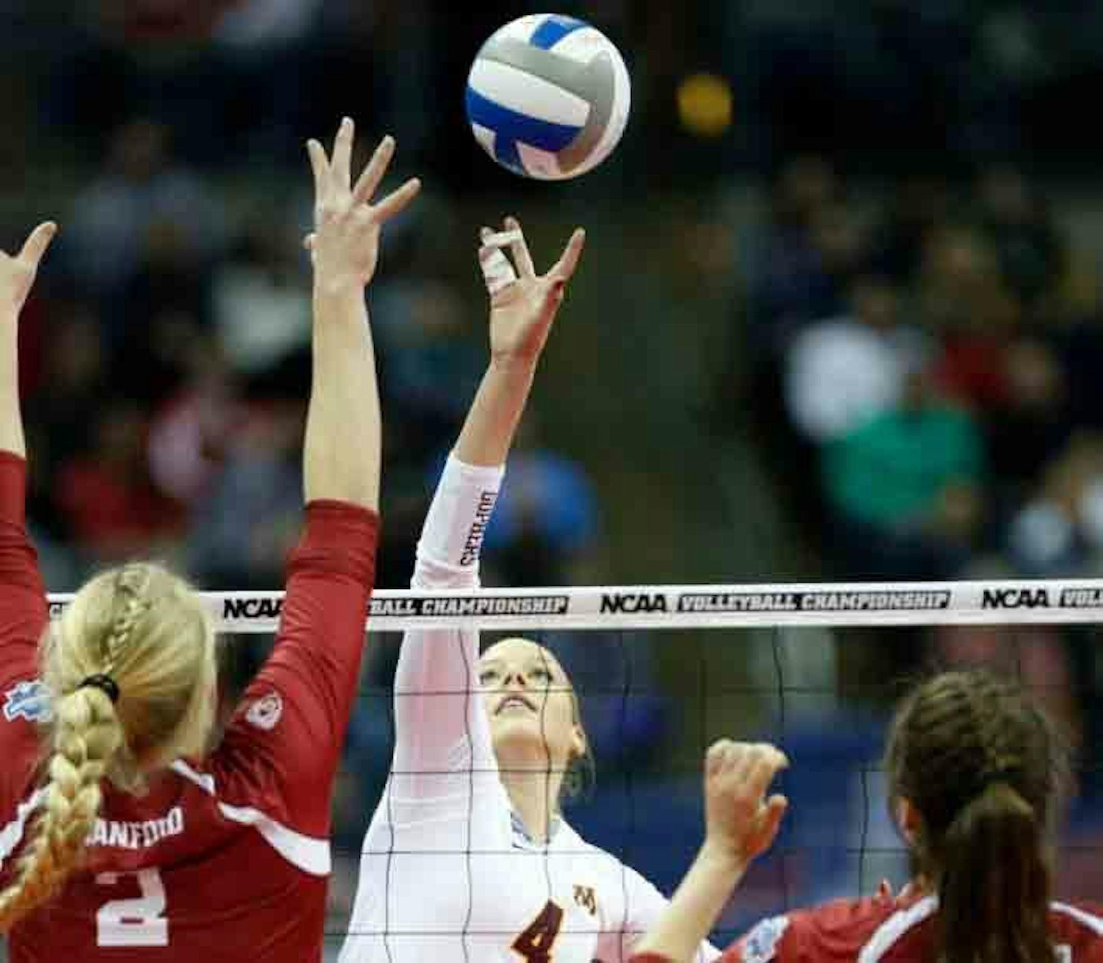 Minnesota middle blocker Paige Tapp, center, tips the ball against Stanford opposite Kathryn Plummer, left, and middle blocker Audriana Fitzmorris during the first set of an NCAA college volleyball championship semifinal game in Columbus, Ohio, Thursday.