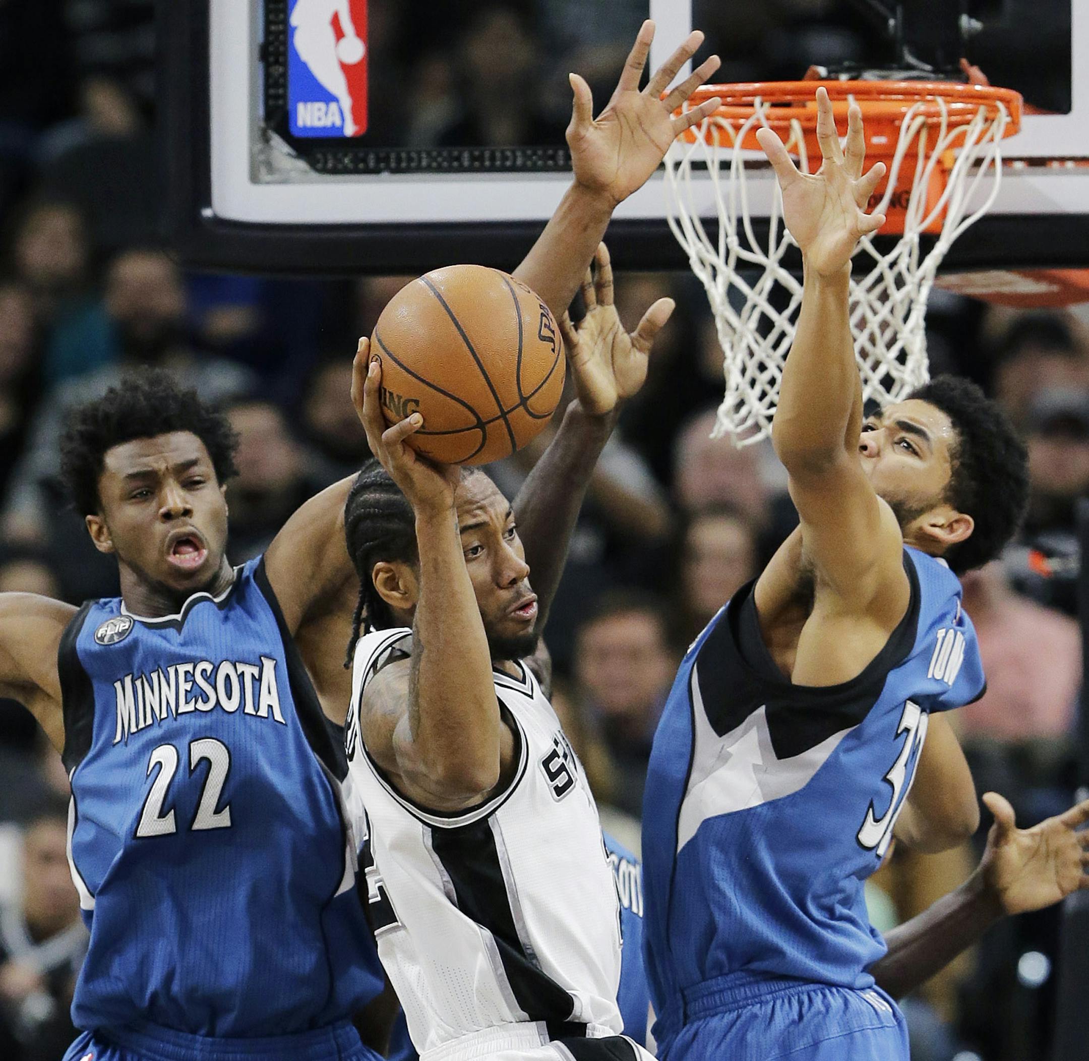 San Antonio Spurs forward Kawhi Leonard, center, passes the ball as Minnesota Timberwolves guard Andrew Wiggins (22) and center Karl-Anthony Towns (32) defend during the first half of an NBA basketball game, Monday, Dec. 28, 2015, in San Antonio. (AP Photo/Eric Gay)