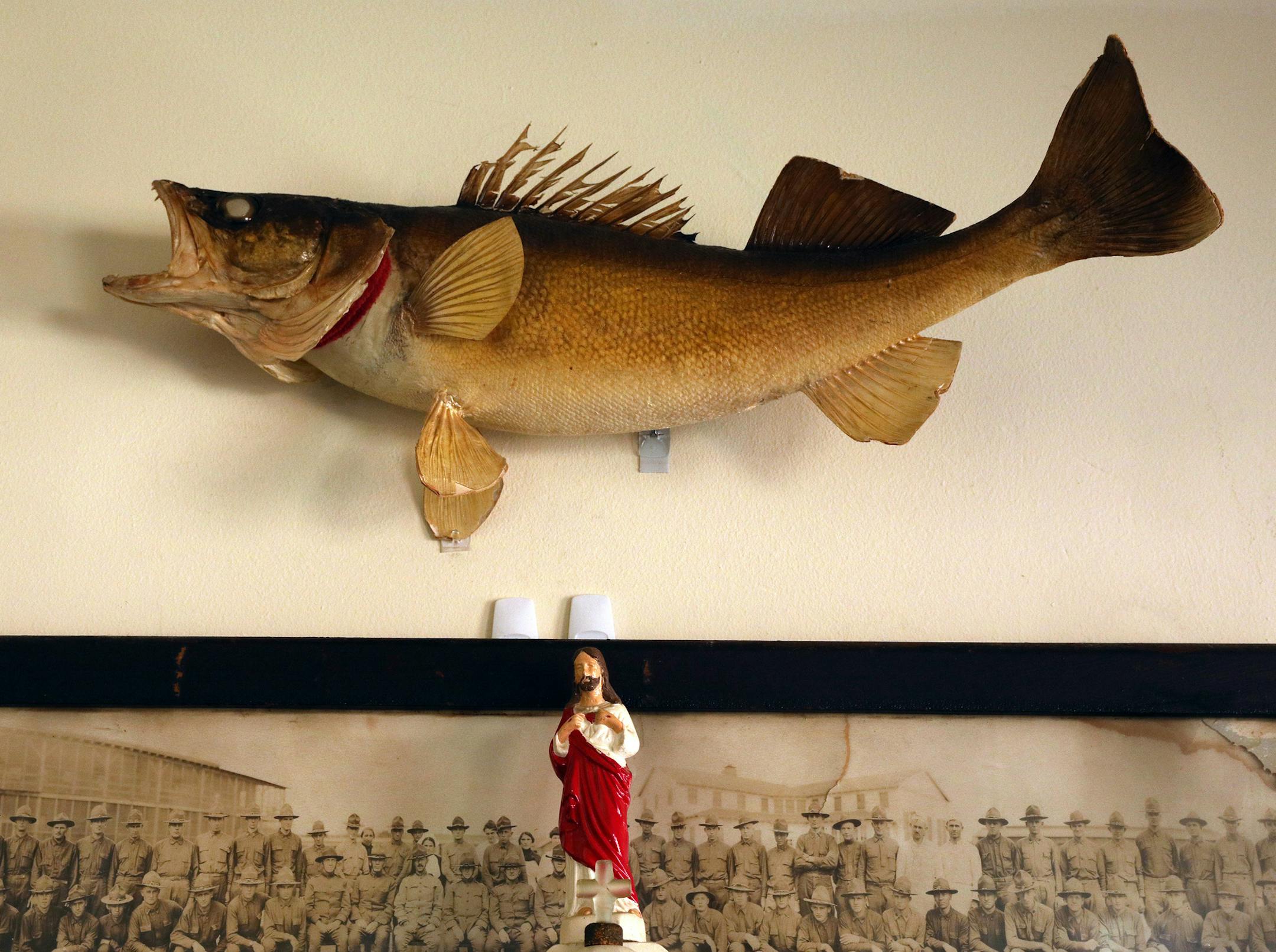 A figure of Jesus sat below a taxidermy fish above the fireplace mantle.