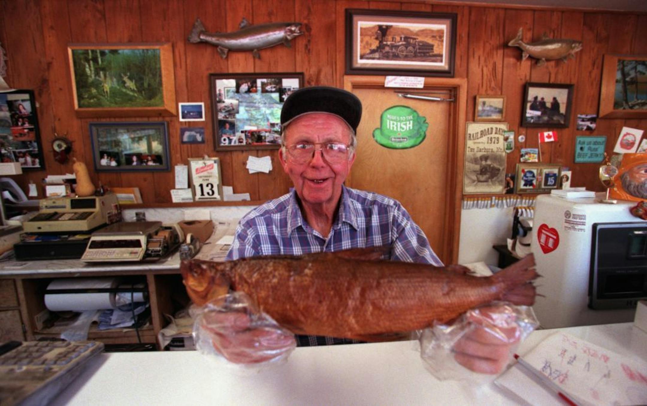 FILE -- In this 1998 file photo, Russ Kendall proudly displays a smoked white fish at his shop in Knife River.