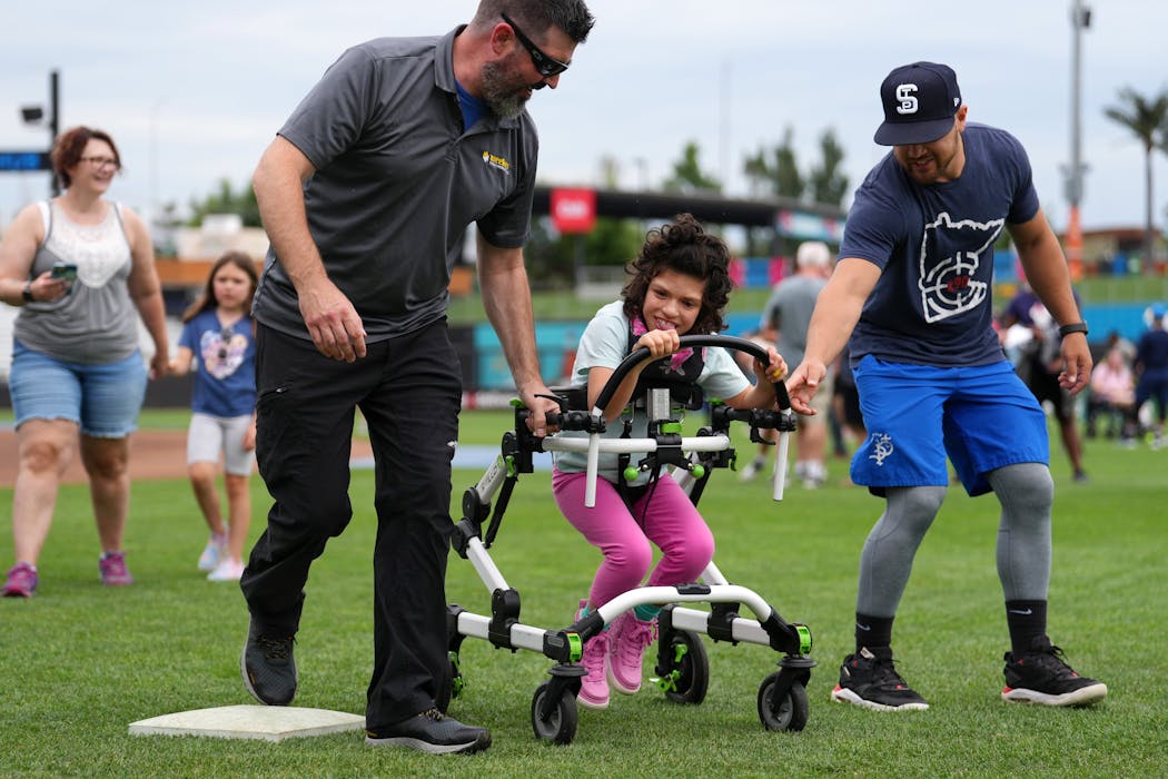 Lee Flaig, left, led his daughter Payton, 12, around the bases with the help of defensive coach Tyler Smarslok.