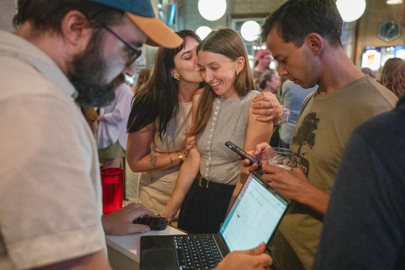 Molly Coleman gets a kiss from supporter and friend Melanie Holland while checking election results with campaign manager Ryan Curtis, far left, on Tuesday night in St. Paul.