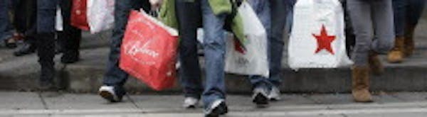 FILE - In this Nov. 26, 2010 file photo, shoppers carry their bags as they walk in downtown Seattle. A new forecast indicates that sales will likely n