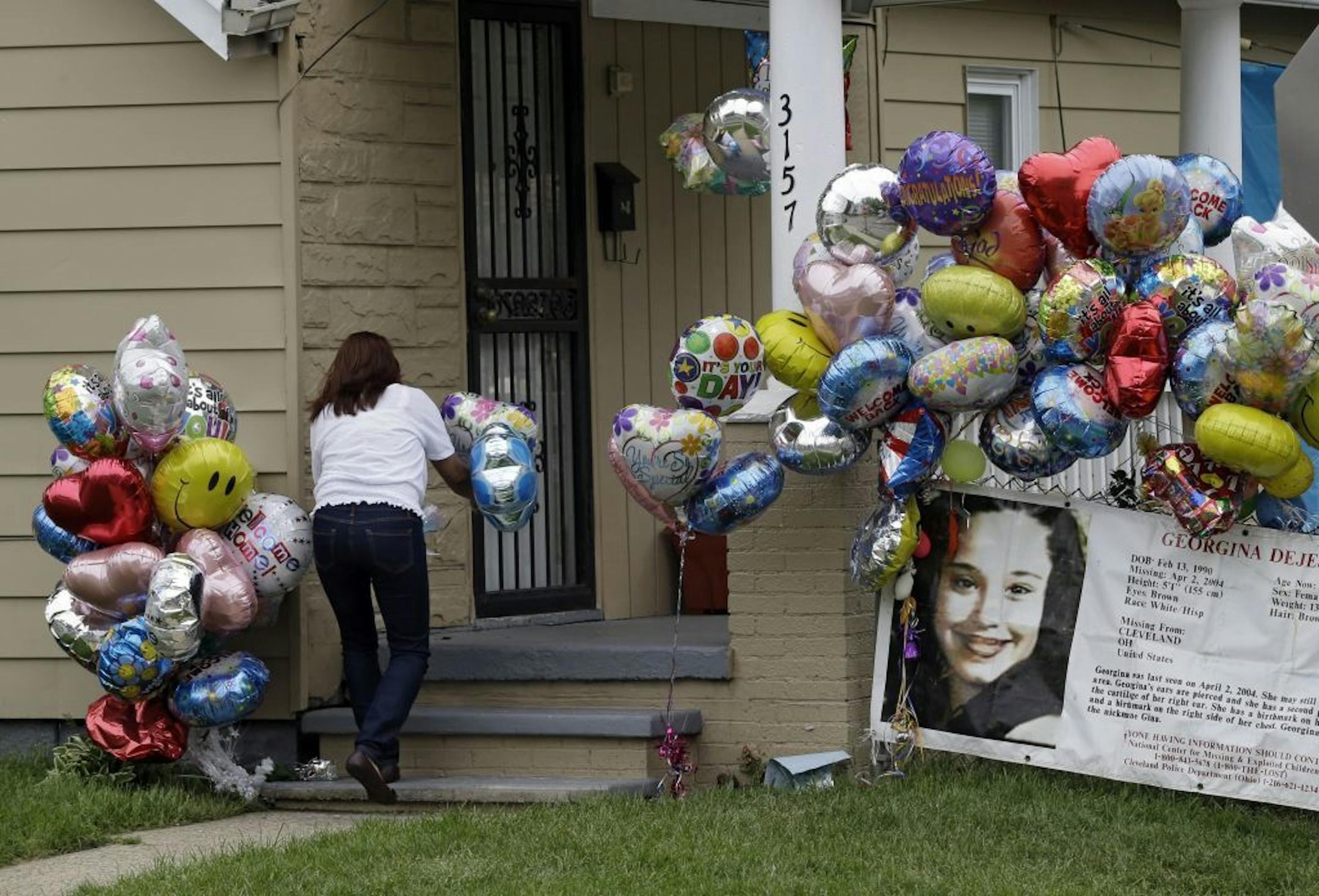 Culema Nevarez adds balloons to a growing tribute outside the home of Gina DeJesus in Cleveland, Friday, May 10, 2013. DeJesus was freed Monday from the home of Ariel Castro where she and two other women had been held captive for nearly a decade.