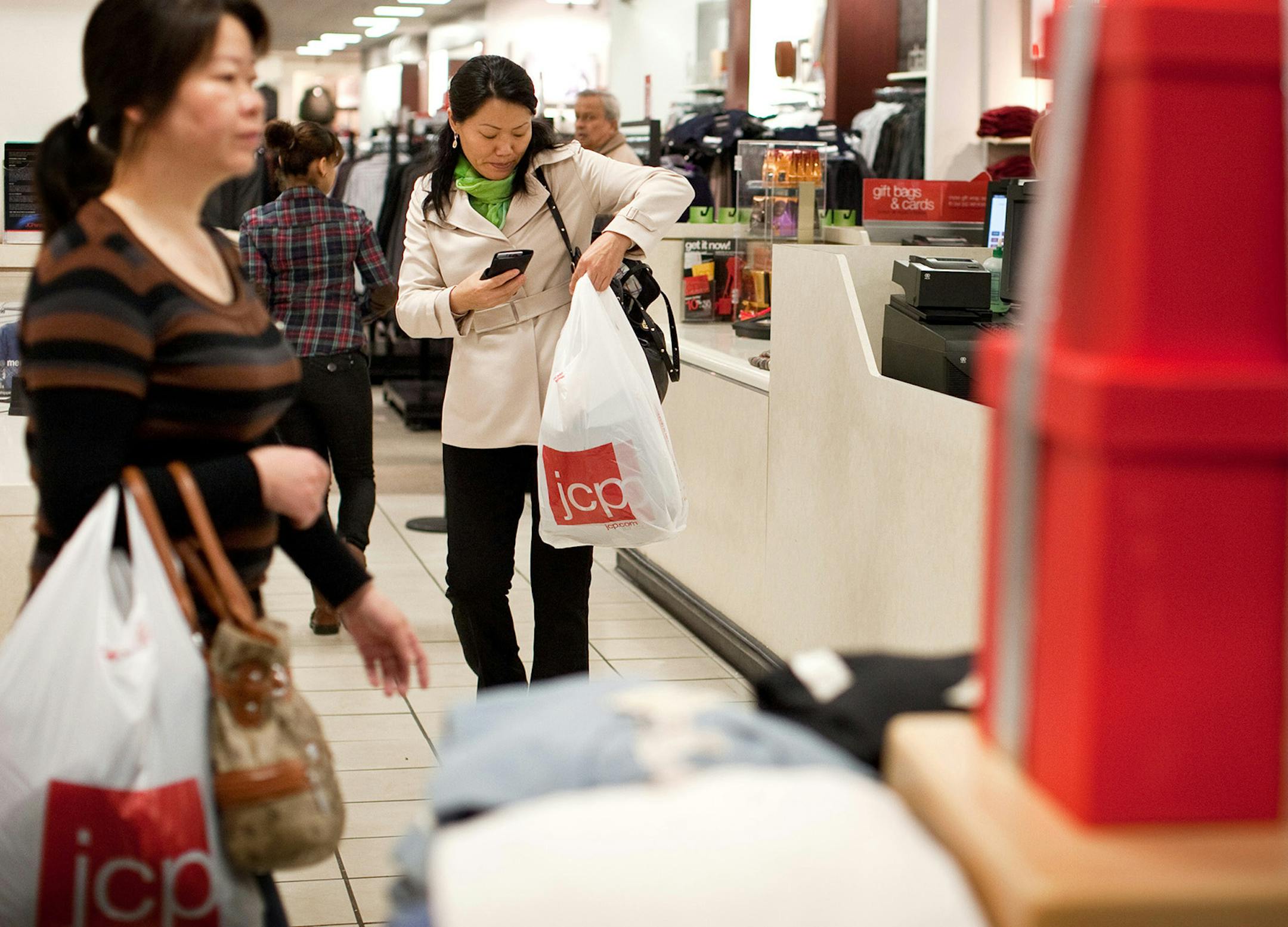 Customers carry J.C. Penney Co. shopping bags in a store at the Queens Center Mall in Elmhurst, New York, U.S., on Thursday, Nov. 3, 2011. Consumer confidence declined last week to its lowest level since the depths of the recession in the first quarter of 2009. Photographer: Emile Wamsteker/Bloomberg ORG XMIT: 131540063