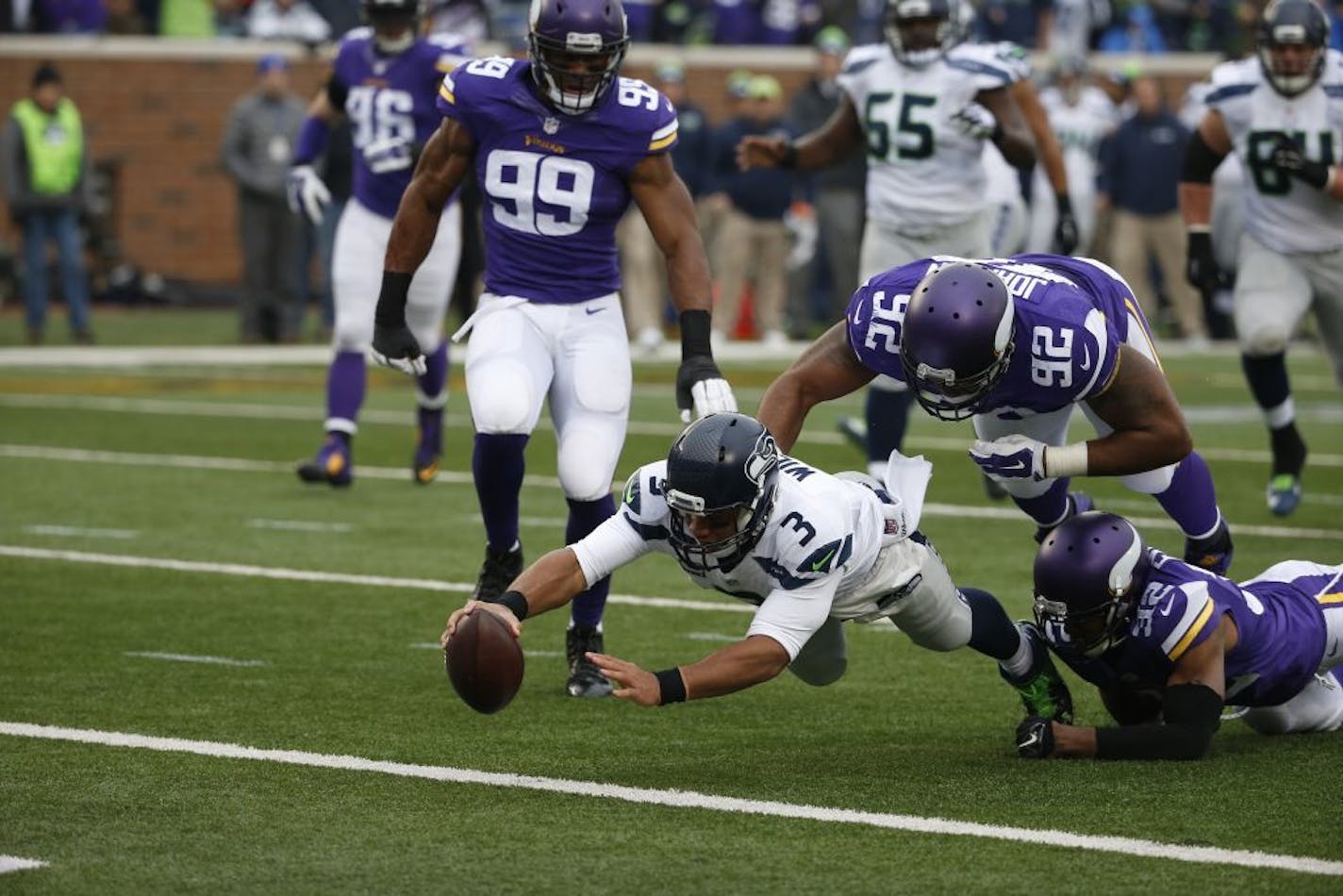 Seattle Seahawks quarterback Russell Wilson (3) dives for a eight-yard touchdown run as Minnesota Vikings cornerback Antone Exum (32) defensive tackle Tom Johnson (92) try to bring him down in the first half of an NFL football game Sunday, Dec. 6, 2015 in Minneapolis.