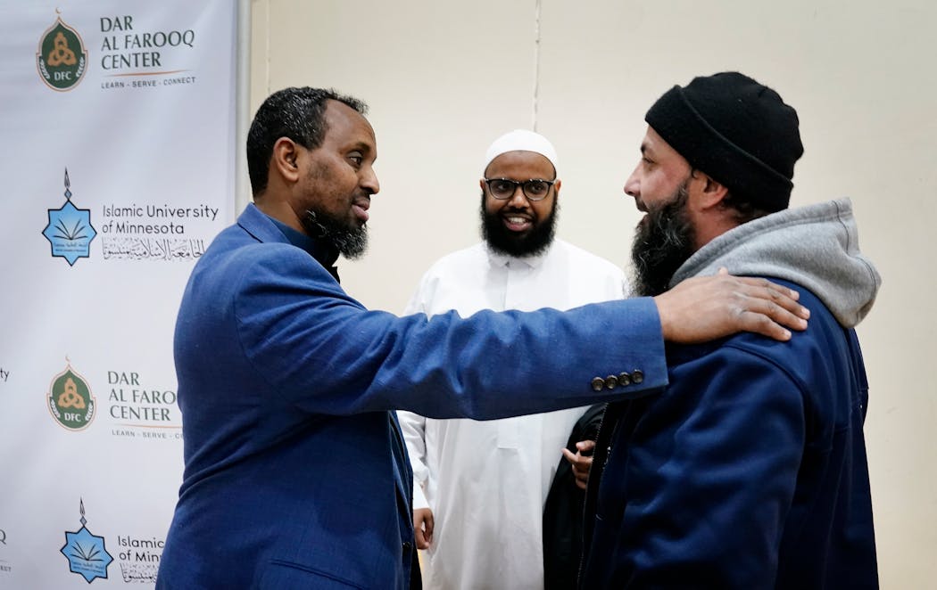 Mohamed Omar, left, greets a worshiper traveling through the Twin Cities as Imam Abdirahman Kariye, middle, looks on during Ramadan at Dar Al-Farooq Islamic Center.