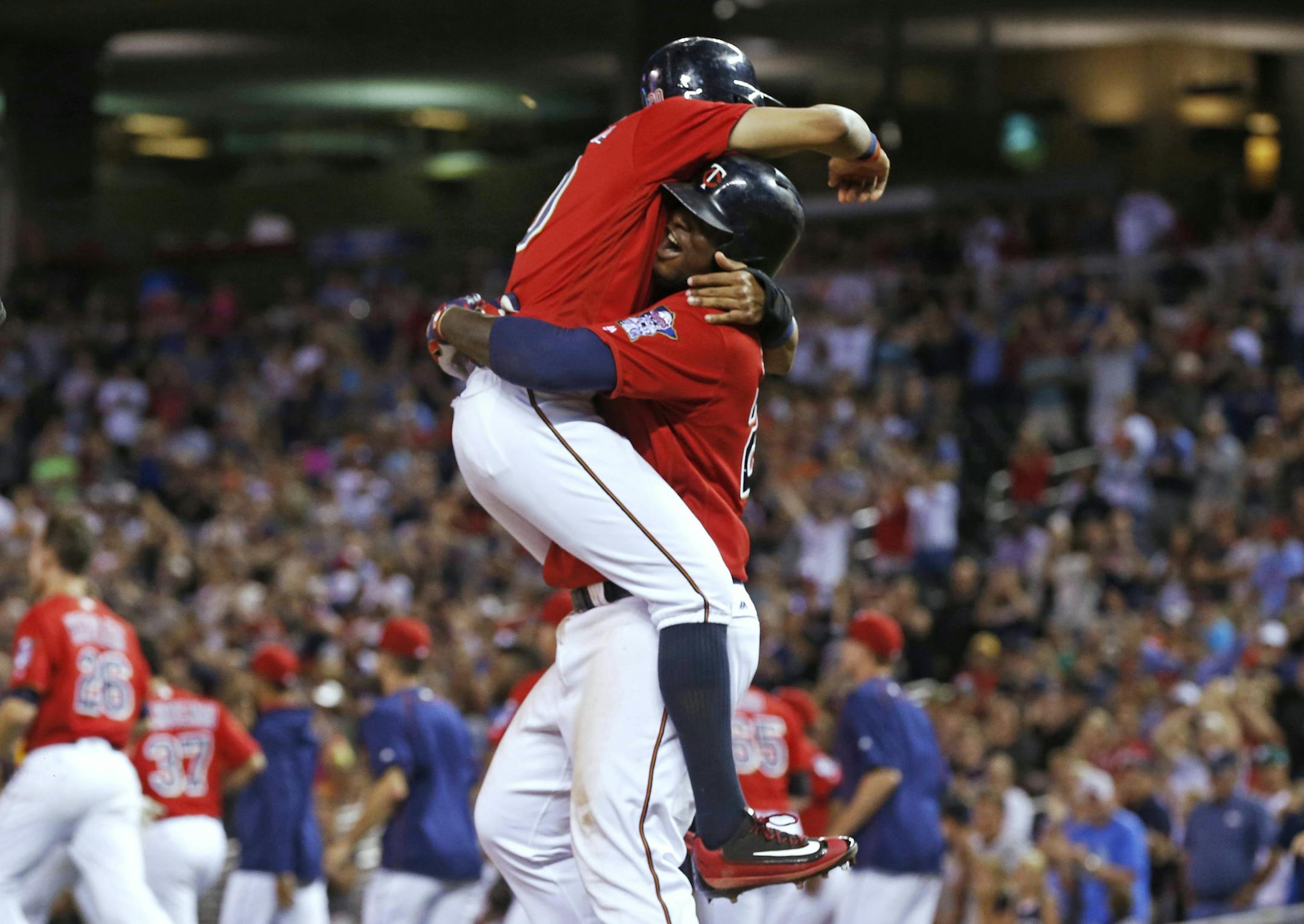 Minnesota Twins' Eddie Rosario is hoisted by Miguel Sano after he scored the winning run on a bases-loaded walk by Chicago White Sox pitcher Tommy Kahnle during the 12th inning of a baseball game Friday, July 29, 2016, in Minneapolis. The Twins won 2-1. (AP Photo/Jim Mone)