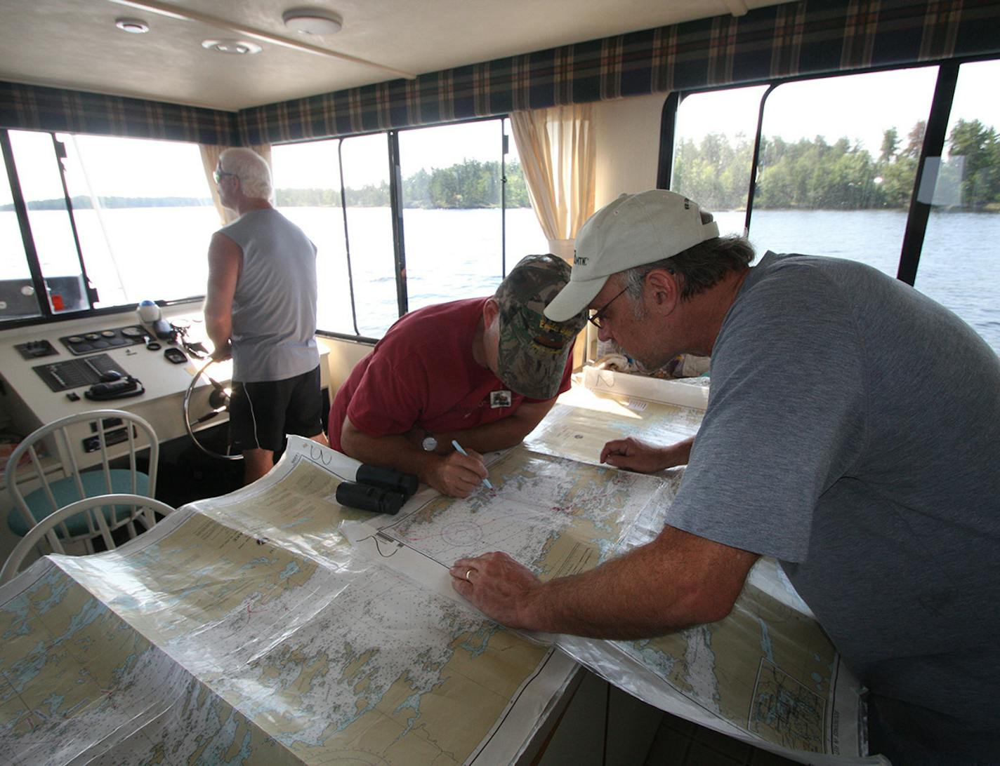 Pat Robischon, left, captained the houseboat on the first morning on Rainy Lake. Bryan Olson and Jon Stein worked on tracking the boat&#x2019;s position. The three are from Sauk Centre.