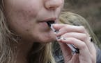 FILE - In this April 11, 2018, file photo, a high school student uses a vaping device near a school campus in Cambridge, Mass. U.S. health regulators 