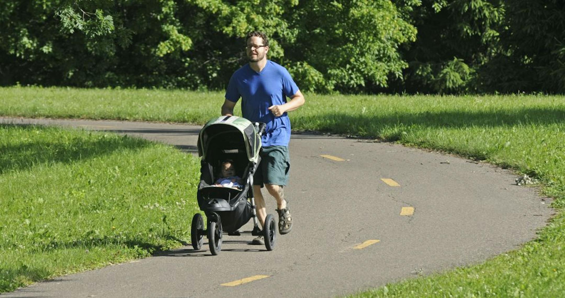 Greg Ripley of Minneapolis trains for the Warrior Dash by pushing his 6-month-old daughter, Mirabai, in her stroller uphill on bike trails in Theodore Wirth Park.