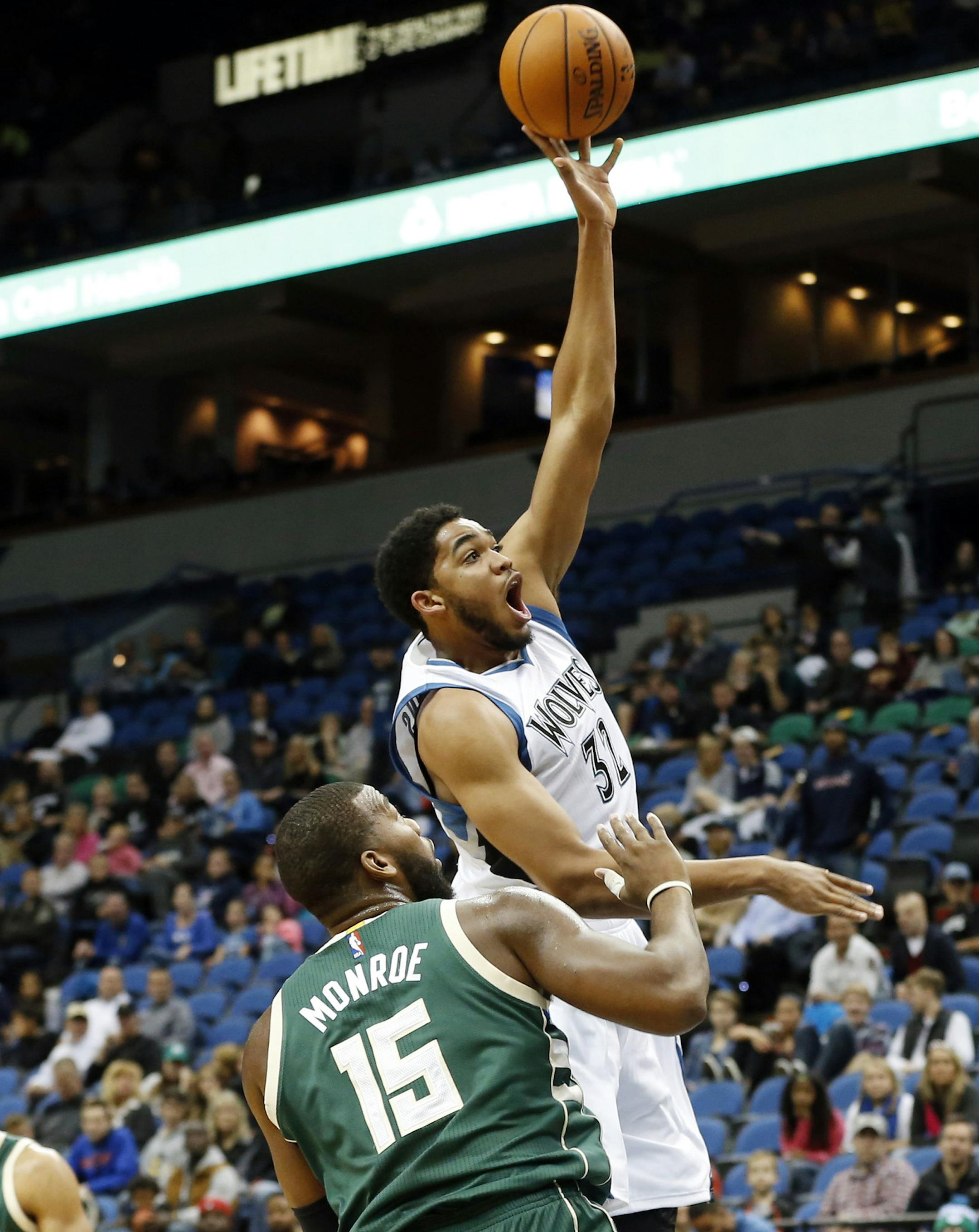 Minnesota Timberwolves’ Karl-Anthony Towns, top, shoots as Milwaukee Bucks’ Greg Monroe watches in the first half of an NBA preseason basketball game, Friday, Oct. 23, 2015, in Minneapolis. (AP Photo/Jim Mone)