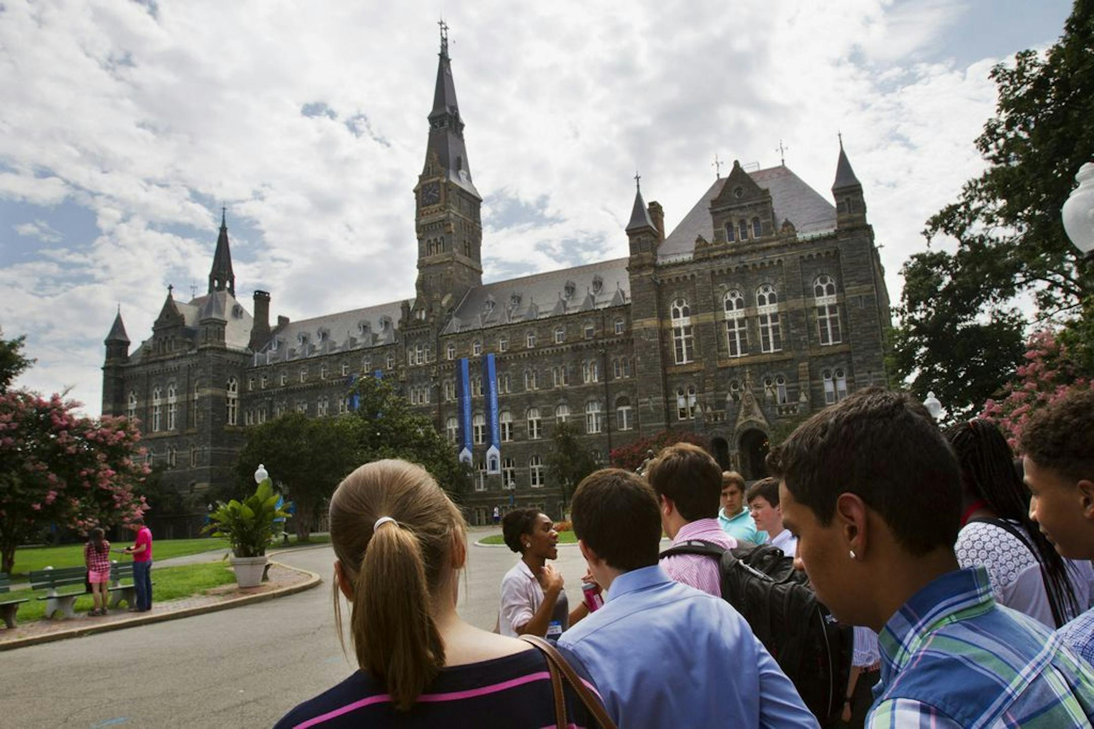 FILE - In this July 10, 2013, file photo, prospective students tour Georgetown University's campus in Washington. Federal authorities have charged college coaches and others in a sweeping admissions bribery case in federal court. The racketeering conspiracy charges were unsealed Tuesday, March 12, 2019, against the coaches at schools including Georgetown, Wake Forest University and the University of Southern California. Authorities say the coaches accepted bribes in exchange for admitting studen