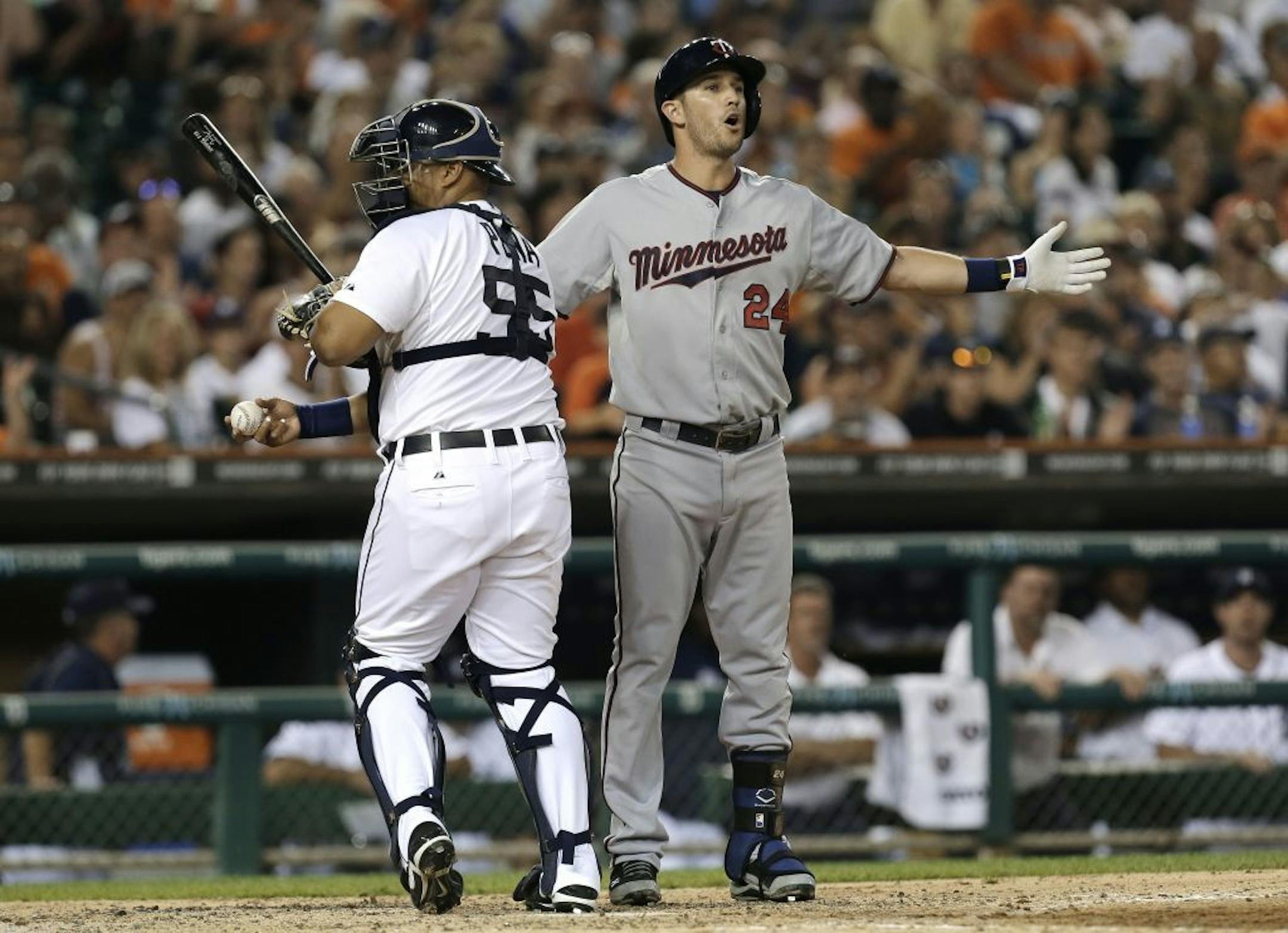 Minnesota Twins' Trevor Plouffe (24) reacts to being called out on strikes by first base umpire Jordan Baker as Detroit Tigers catcher Brayan Pena (55) heads to the dugout in the fifth inning of a baseball game in Detroit, Tuesday, Aug. 20, 2013. (AP Photo/Paul Sancya) ORG XMIT: MIN2013082020371177