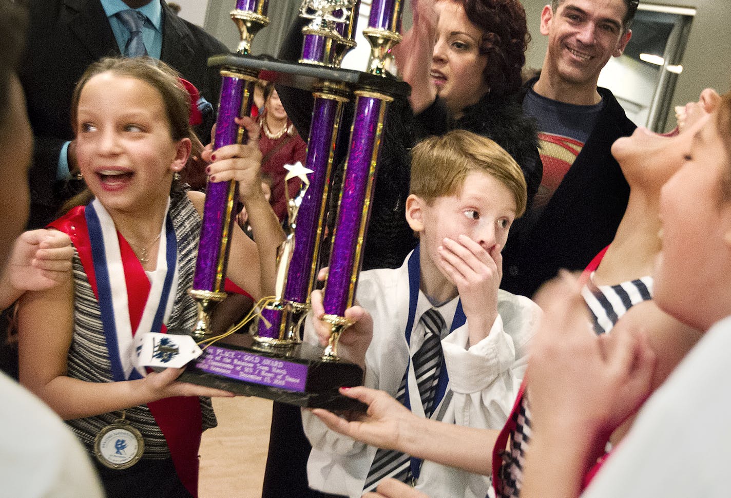 10-year-olds Kieran Pavlica, right, and Cayenne Ramirez react to their team winning first place in the Colors of the Rainbow Dancing Classrooms Team Match presented by Heart of Dance at Dancers Studio in St. Paul December 13, 2015. Two of the five event judges, Rebecca and Eliecer Ramirez present the trophy. (Courtney Perry/Special to the Star Tribune)