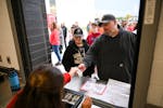 Paul Kerns, of Andover, is handed game tickets and change at the box office beside his 11-year old son, Logan, before the start of a football game bet