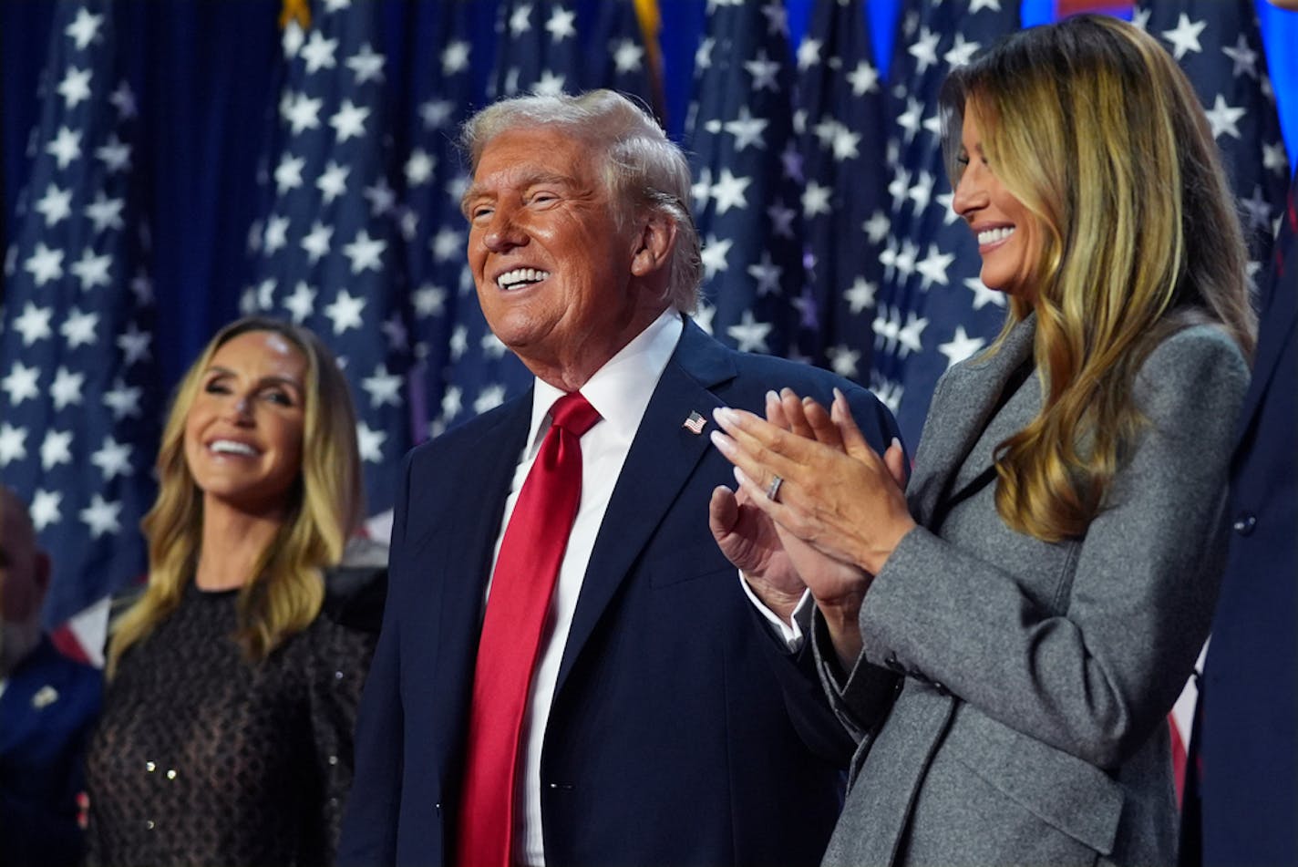 Republican presidential nominee former President Donald Trump stands on stage with former first lady Melania Trump, as Lara Trump watches, at an election night watch party at the Palm Beach Convention Center, Wednesday, Nov. 6, 2024, in West Palm Beach, Fla.