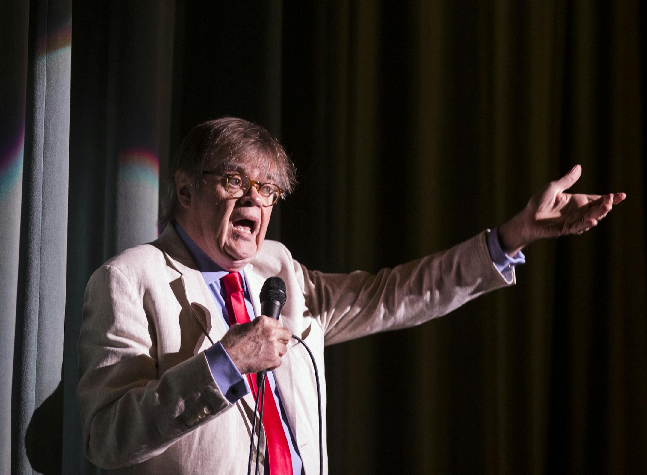 Garrison Keillor greets the audience, asking them to stand and sing "The Star Spangled Banner."