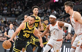 Golden State Warriors' Stephen Curry (30) drives against San Antonio Spurs' Devonte' Graham (4) and Zach Collins during the second half of an NBA bask