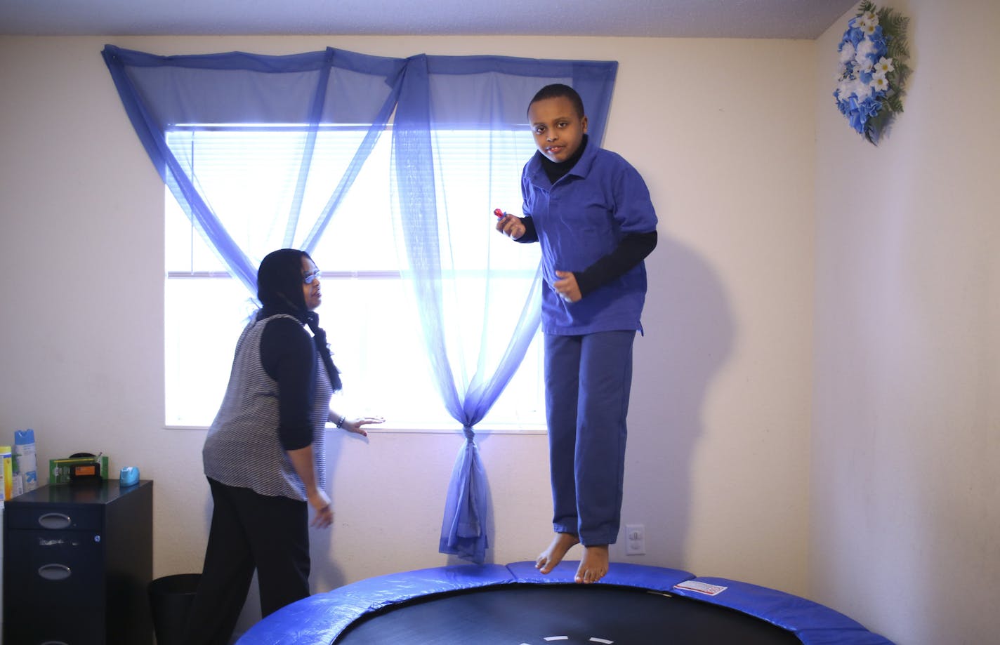 A University of Minnesota study released Monday, December 16, 2013, has found elevated rates of Autism among children who are white or Somali in the Twin Cities when compared to black or Hispanic youngsters. Idil Abdull with her eleven year-old son, Abdullahi, who was on a trampoline in his therapy room at their home in Savage Monday afternoon, December 16, 2013. Abdullahi, who has been diagnosed with Autism, stopped at home for a snack before heading to a therapy appointment. ] JEFF WHEELER &#x