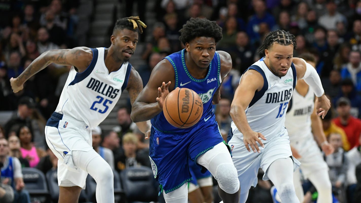 Minnesota Timberwolves guard Anthony Edwards, center, drives past Dallas Mavericks guard Reggie Bullock (25) and Dallas Mavericks guard Jalen Brunson during the first half of an NBA basketball game Friday, March 25, 2022, in Minneapolis. The Timberwolves won 116-95. (AP Photo/Craig Lassig)