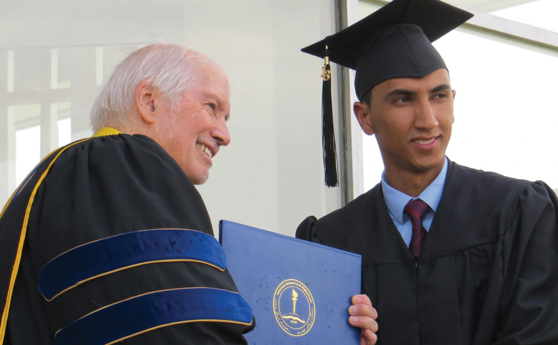 Abdul Ghani Popal, a recent graduate of American University of Afghanistan, said that better education can help his generation transcend age-old rivalries. Here, he received his diploma from the school’s president, C. Michael Smith.