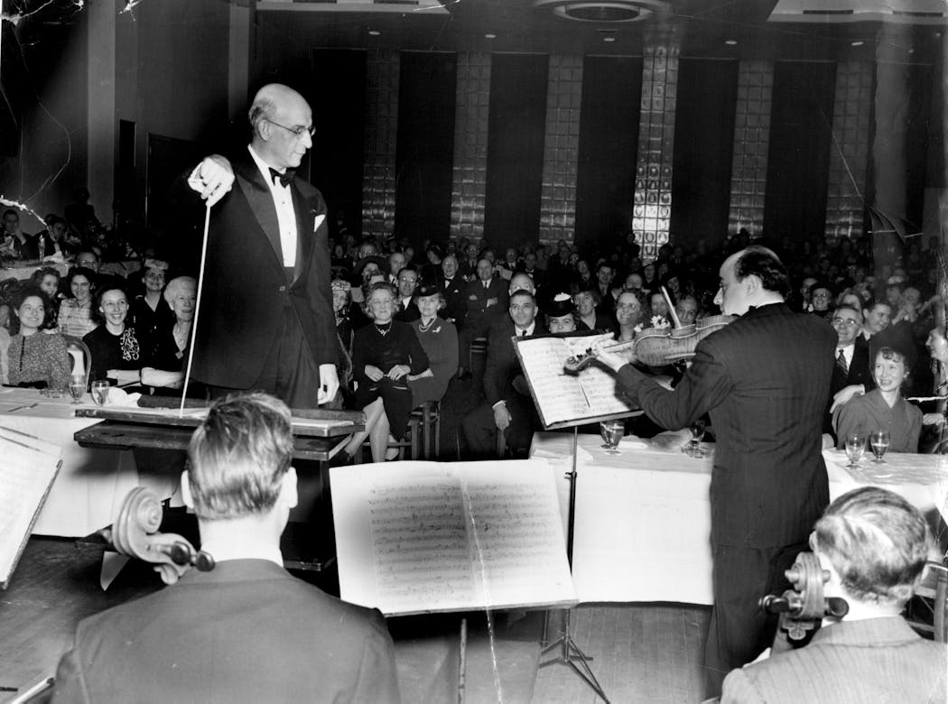 Dmitri Mitropoulos, left, watches a violist's cadenza during a symphony dinner at the Radisson hotel in 1941.