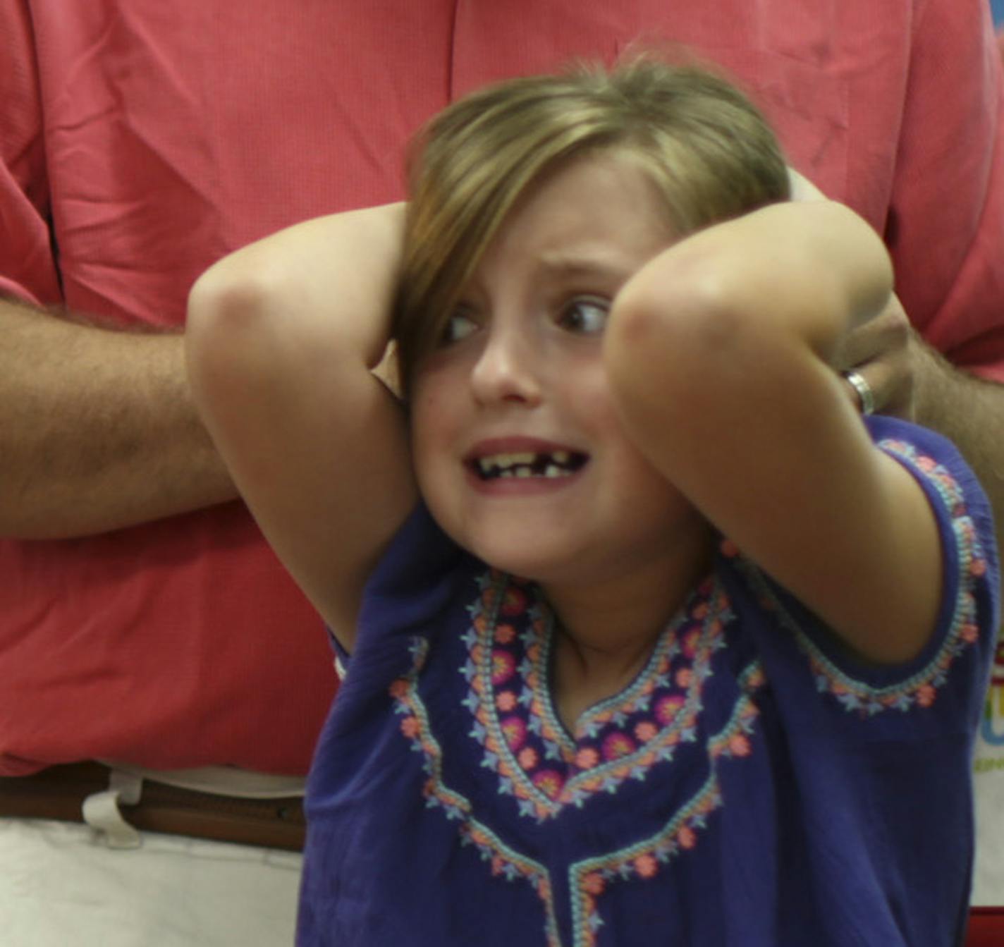 Sophia Korman, 7, reacted as her dad, Mike, fixed her hair in a ponytail during the class at Kids Hair.