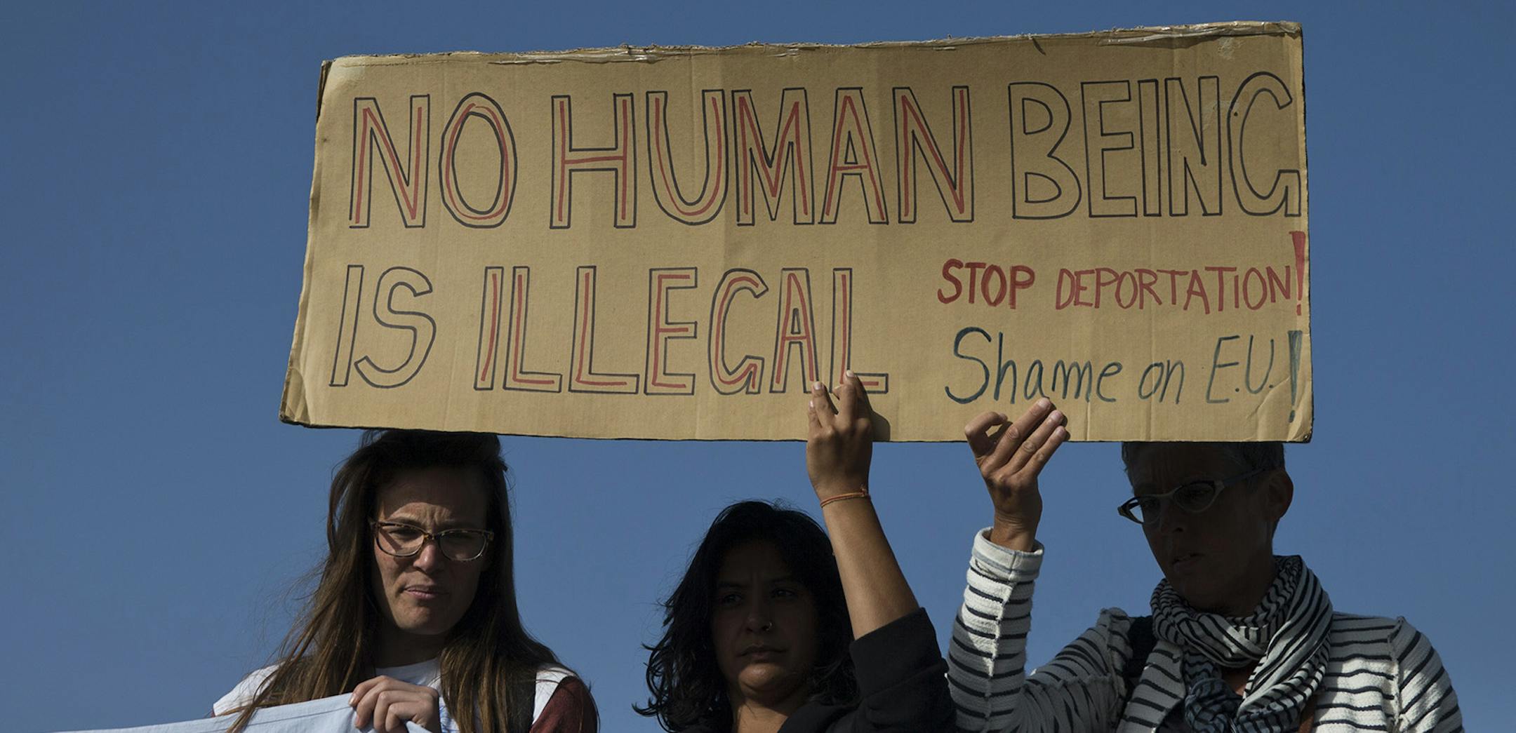 Protester hold a banner as they demonstrate against deportations planned at the port of Mytilini, Lesbos island, Greece, on Monday, April 4, 2016, during the first day of the implementation of the deal between EU and Turkey. Under heavy security, the first 135 migrants were being escorted onto the boats as dawn broke Monday by officers from the EU border protection agency, Frontex, to nearby ports on the Turkish coast, under the plan which has been strongly criticized by human rights groups.(AP