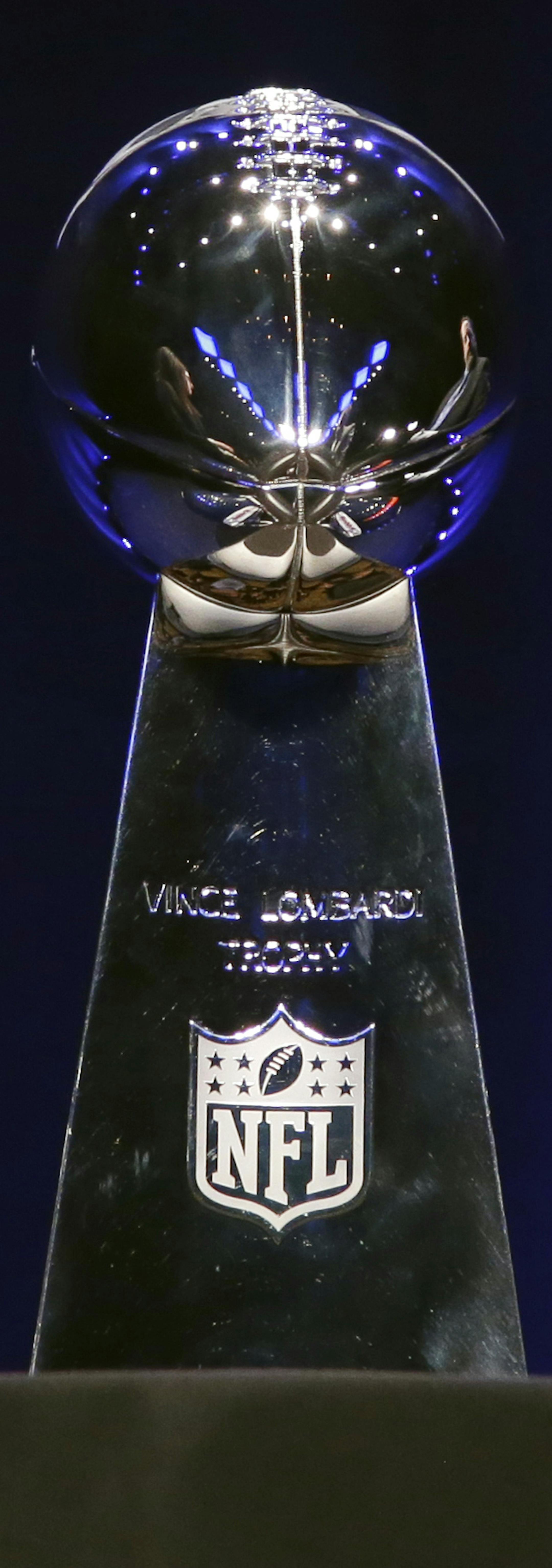 The Vince Lombardi Trophy is displayed between the Seattle Seahawks and the Denver Broncos helmets before a news conference Friday, Jan. 31, 2014, in New York. The Seahawks and the Broncos are scheduled to play in the NFL Super Bowl XLVIII football game on Sunday, Feb. 2, at MetLife Stadium in East Rutherford, N.J. (AP Photo/Charlie Riedel)