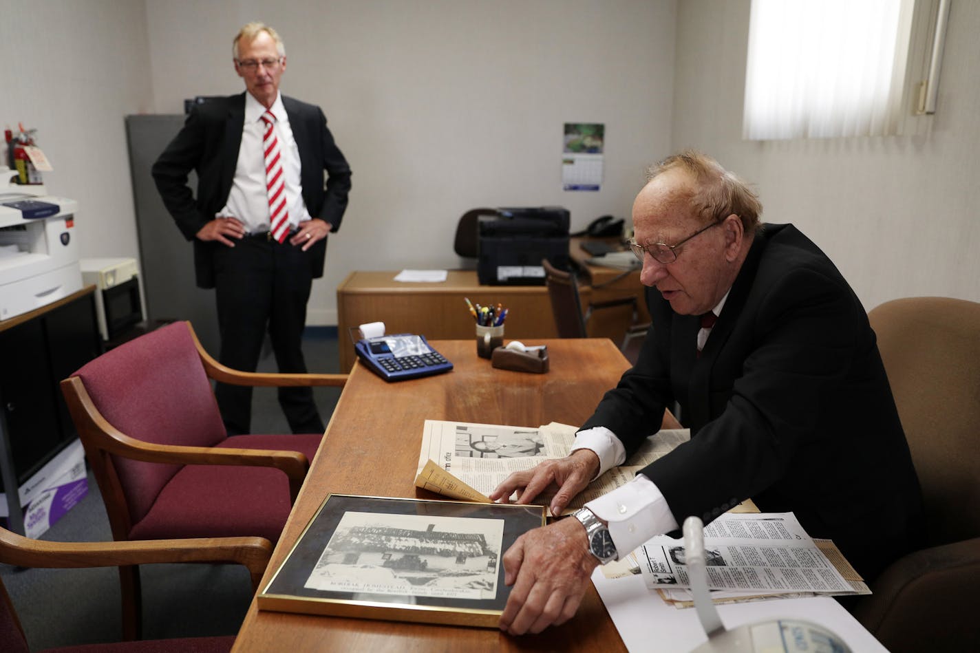 Al Kordiak, right, and Jim Kordiak in the tax business they've run together for decades, as Al reached for a weathered photo of his family's home in Czechoslovakia.