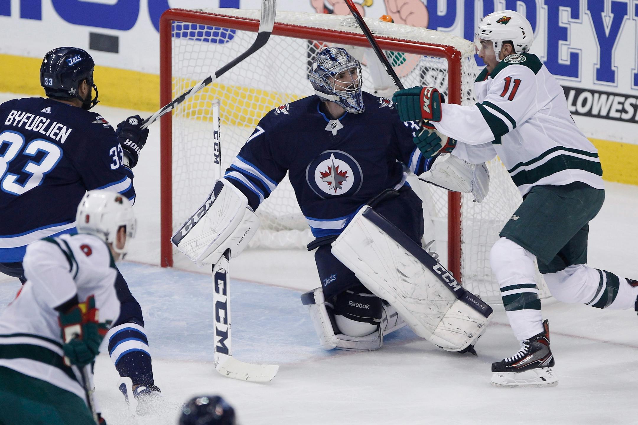 Winnipeg Jets goaltender Connor Hellebuyck (37) looks up at Minnesota Wild's Zach Parise (11) as he saves a shot during the first period of Game 1 in an NHL hockey first-round playoff series Wednesday, April 11, 2018, in Winnipeg, Manitoba.