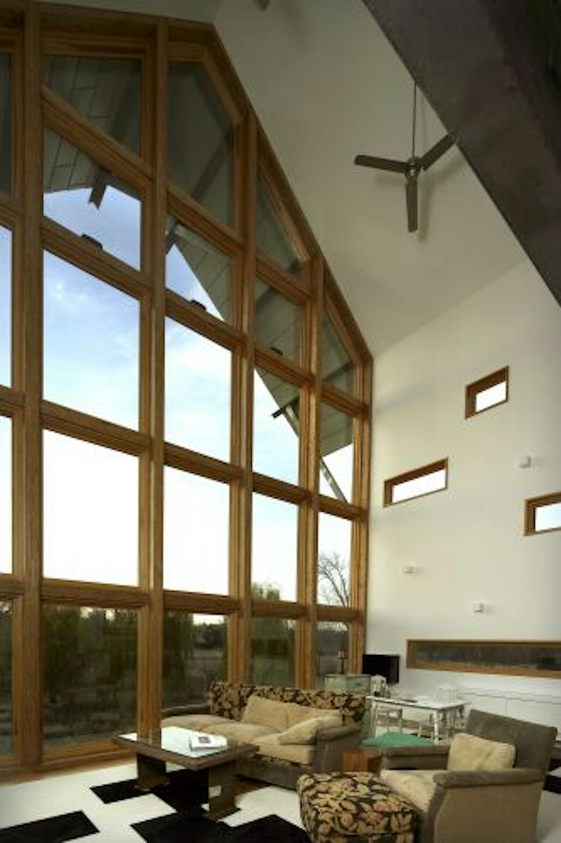 The two-story living room features a wall of windows.